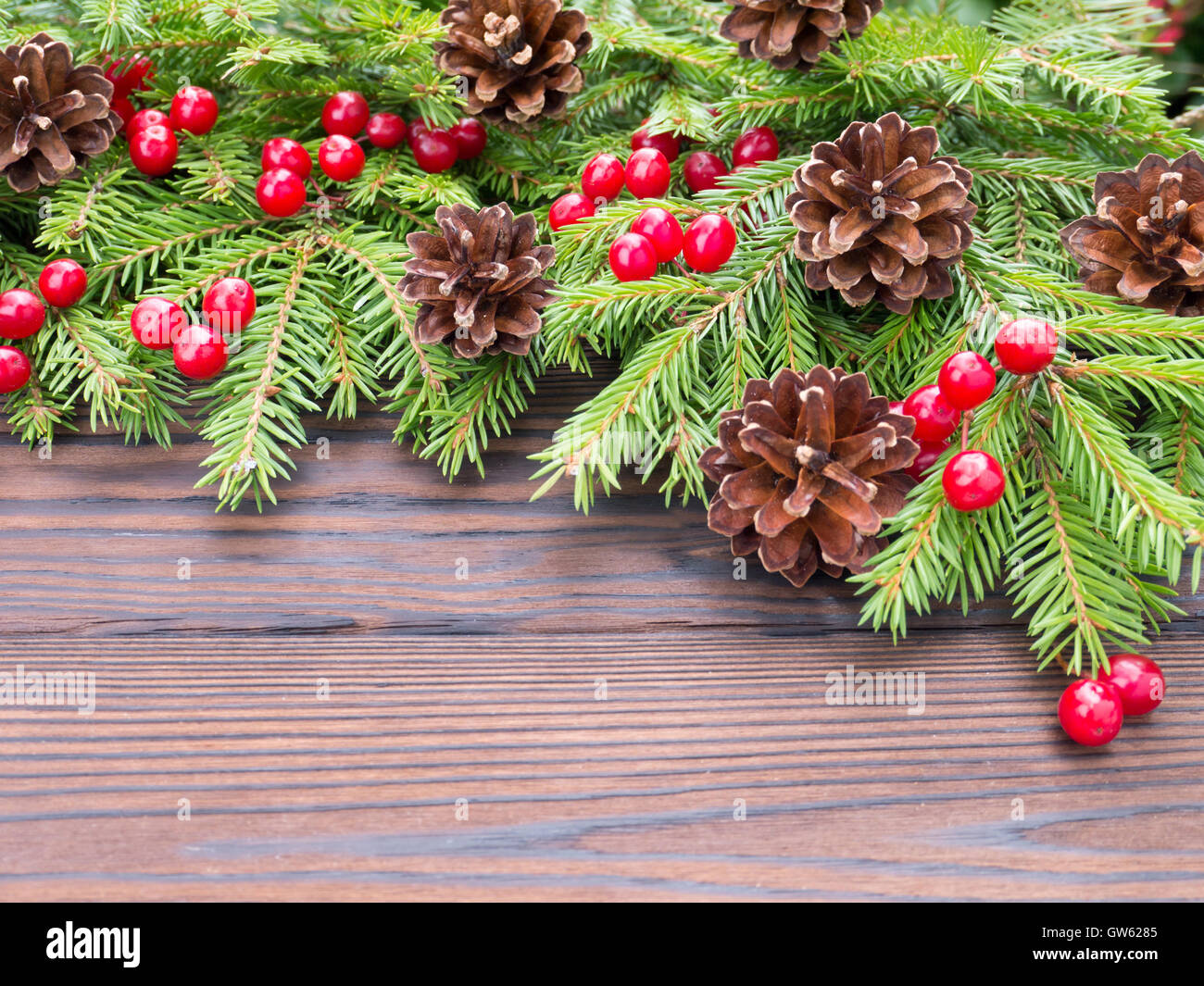 Christmas tree branches with red berries and cones on the drak wooden ...