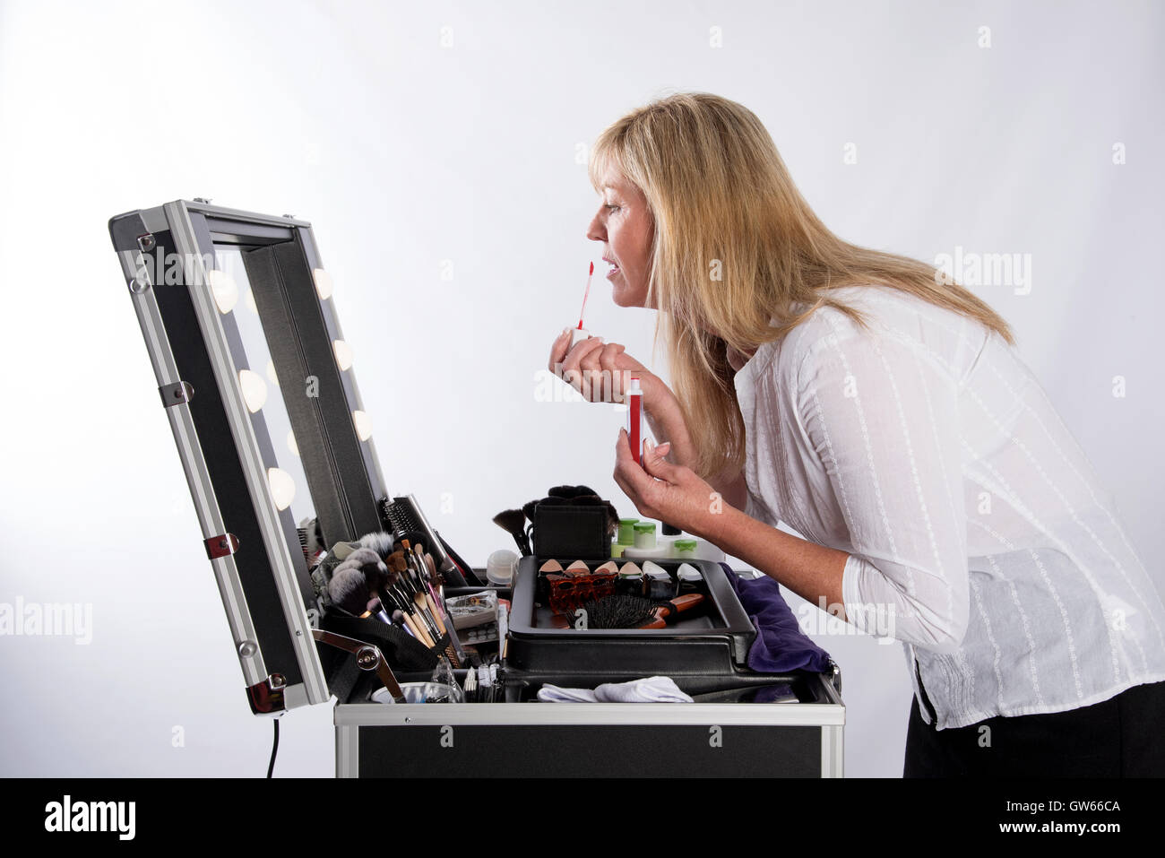 Woman applying lip gloss from a large make up box Stock Photo