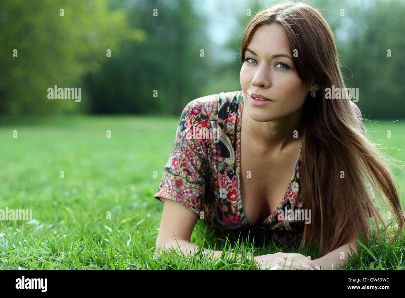 Portrait of young woman lying on a green lawn Stock Photo - Alamy