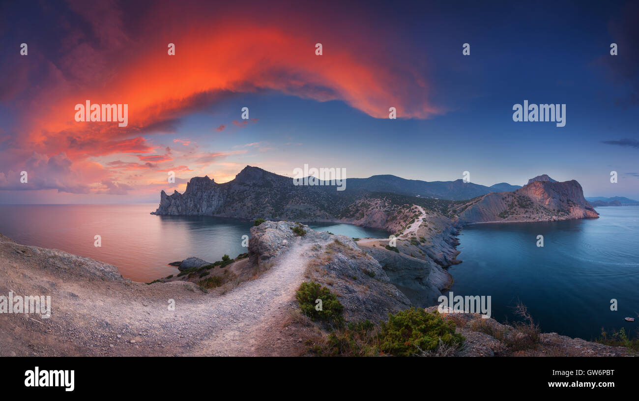 Beautiful panoramic landscape with mountains, sea, blue sky and beautiful colorful red clouds at sunset in Crimea. Sunset Stock Photo