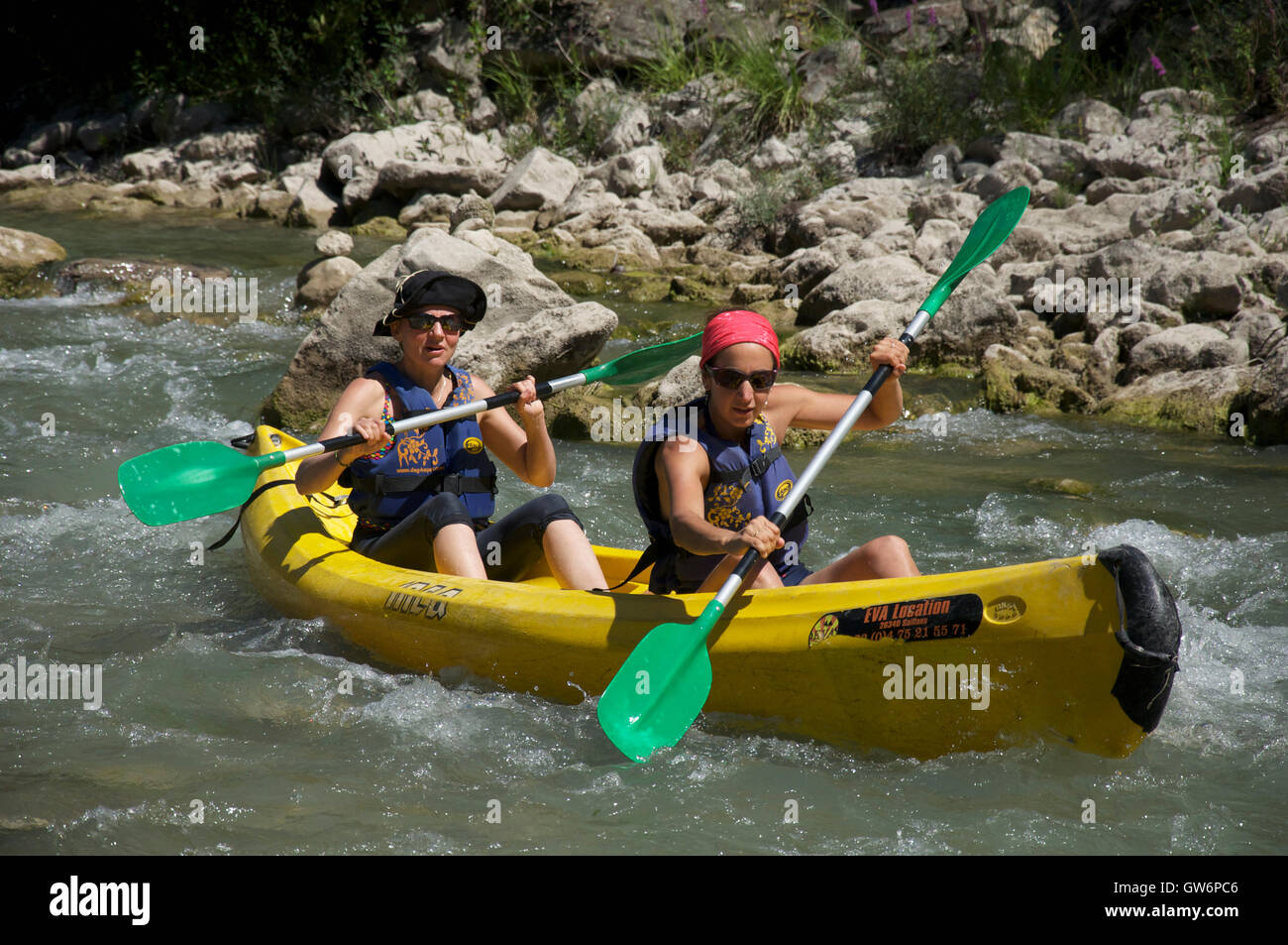Tourism, watersports, tourists. Two young women canoeing down the fast