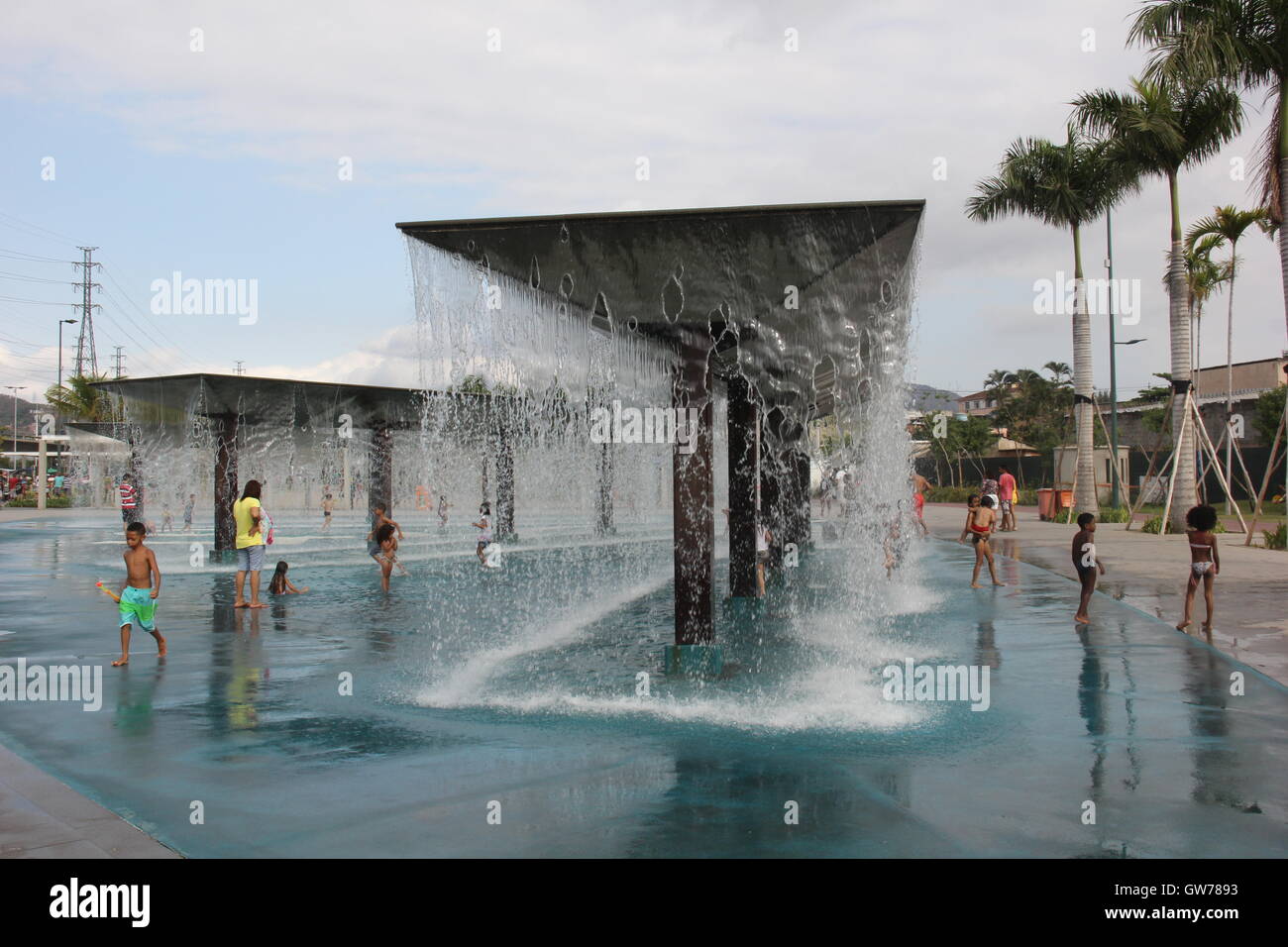 Children have fun in the water cascades of Madureira Park. The Madureira Park is the third largest leisure area of the city of Rio de Janeiro. The site, which is built on the banks of the railway line that crosses several suburban neighborhoods of Rio and is a poor area of the city. The site was recently expanded and gained new services such as tennis courts for free use, new bike paths and new areas of leisure and entertainment. On site we highlight the artificial lakes made in the shape and colors of the Olympic Rings and also the 'artificial beaches' where water cascades make the joy of chi Stock Photo