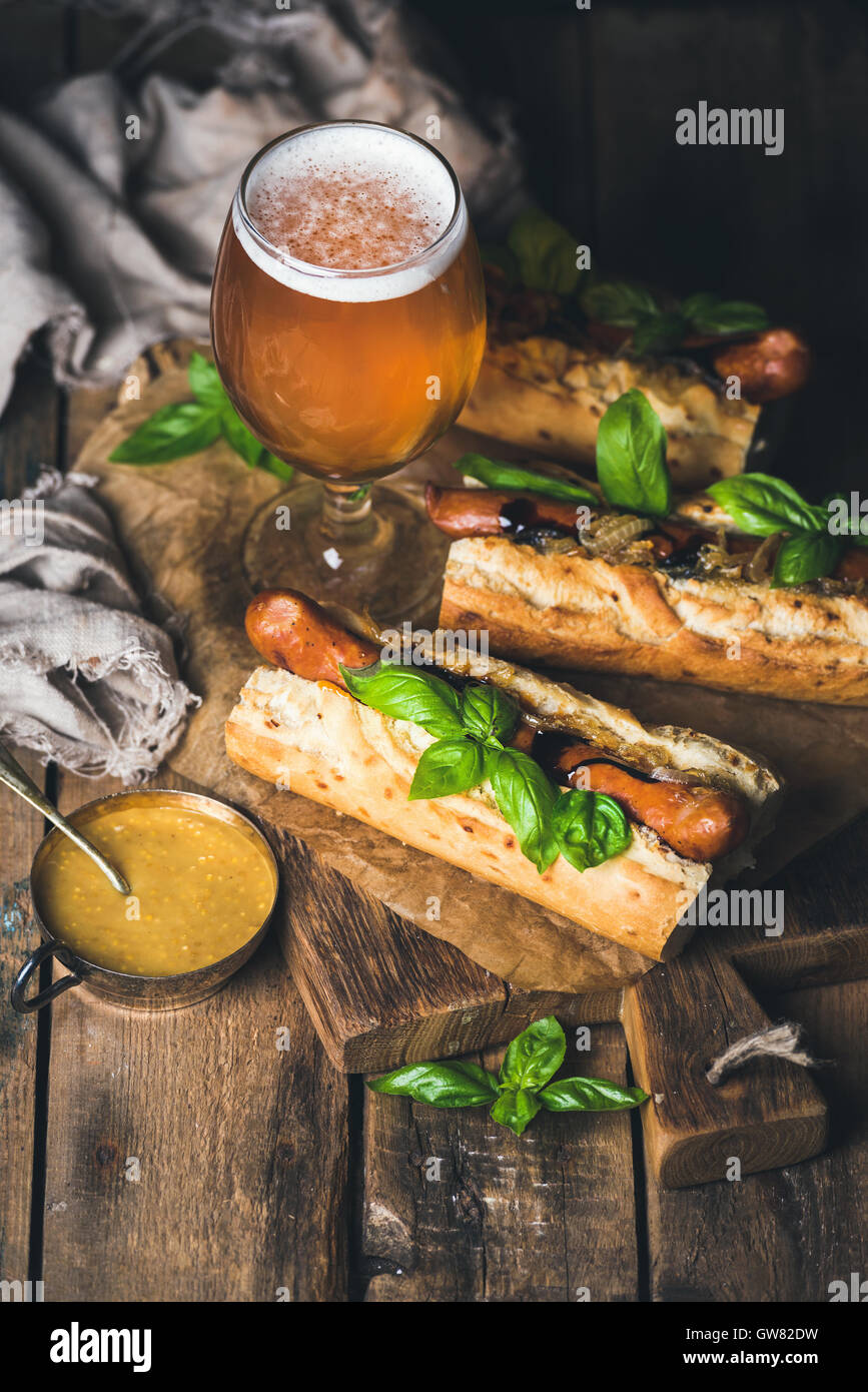 Glass of wheat beer and grilled sausage dogs in baguette Stock Photo