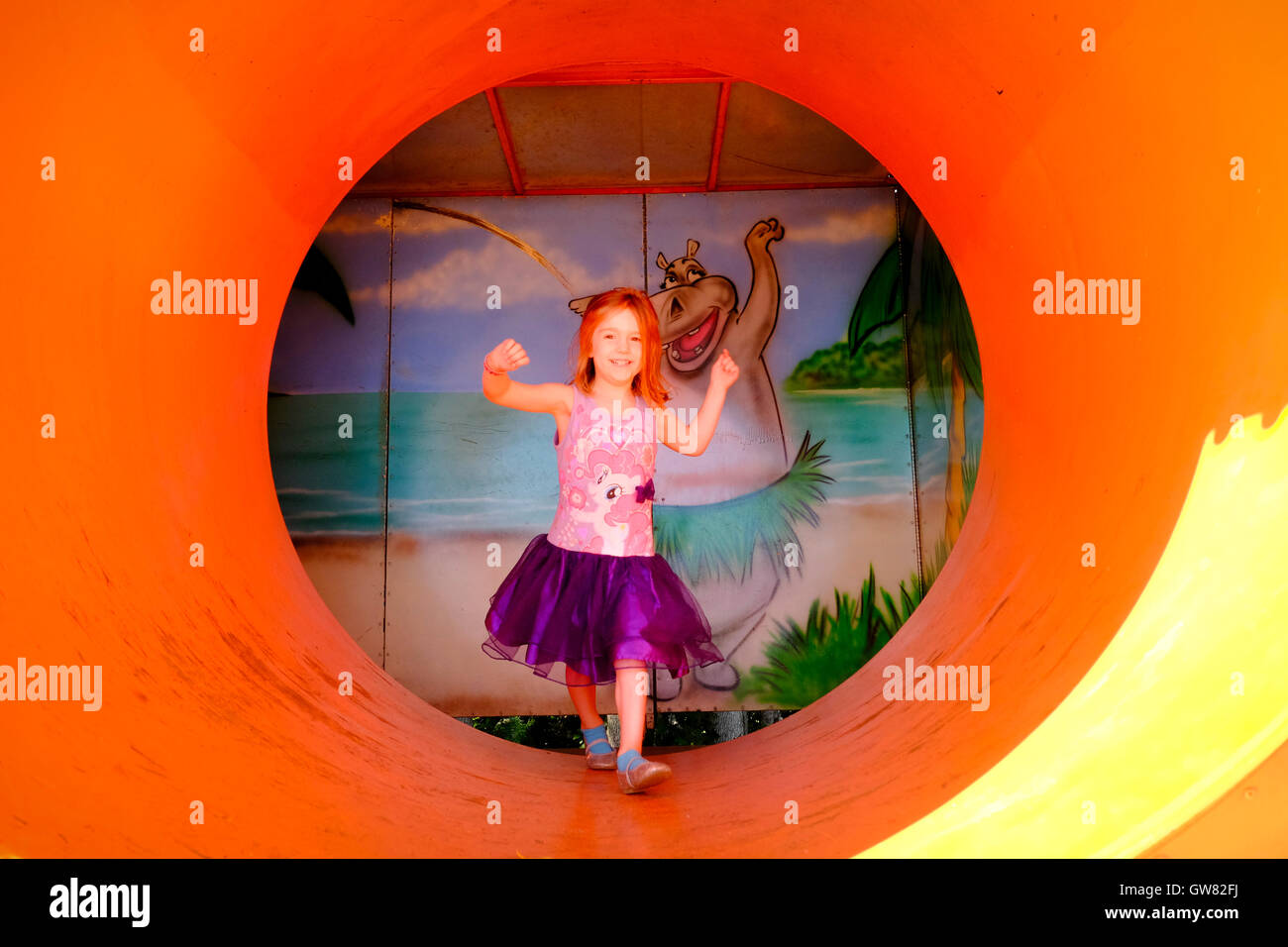 Young girl at play in the final room of a fun house with a moving tubular exit Stock Photo