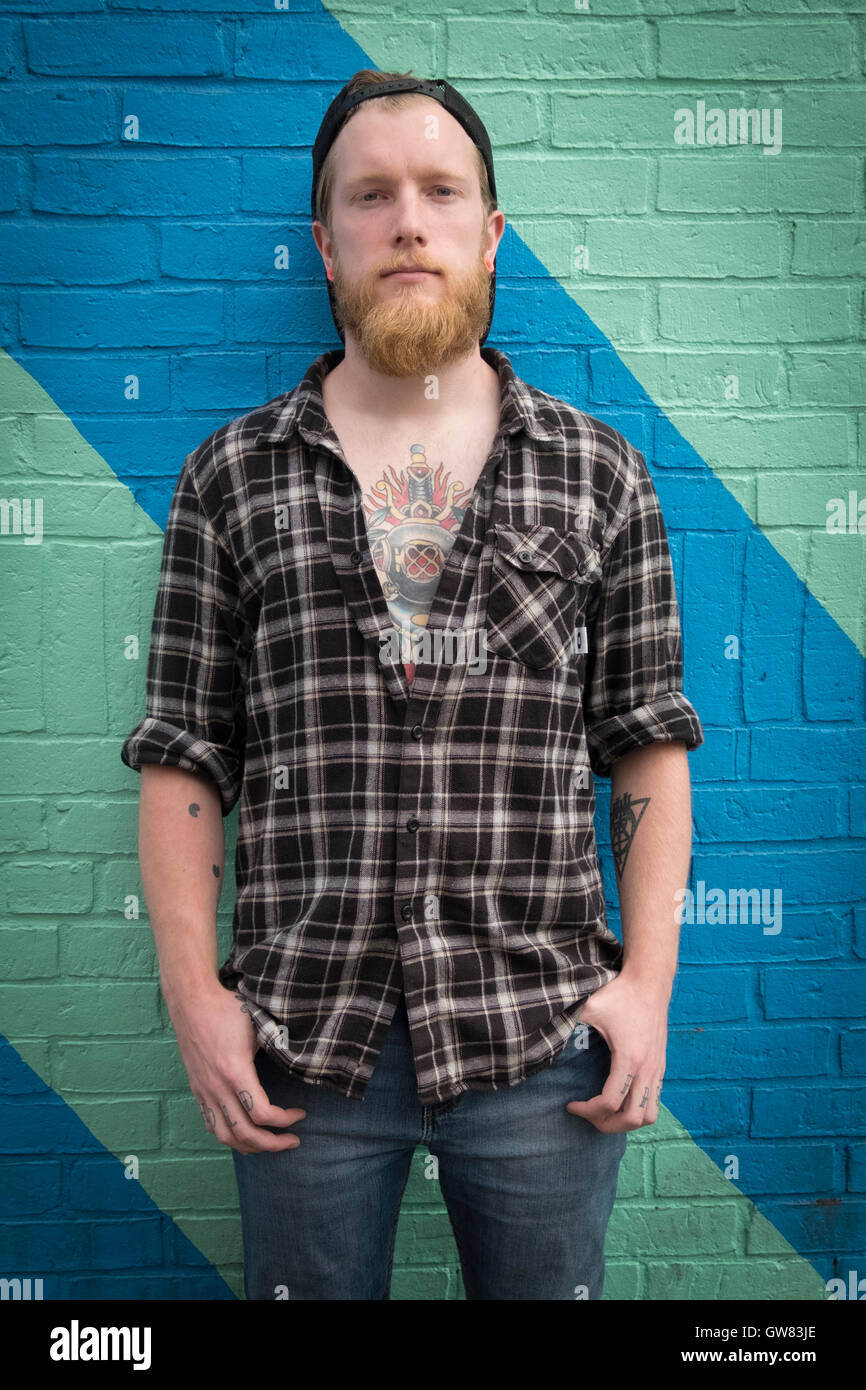Young male hipster with tattoo, flannel shirt, beard and baseball cap Stock Photo