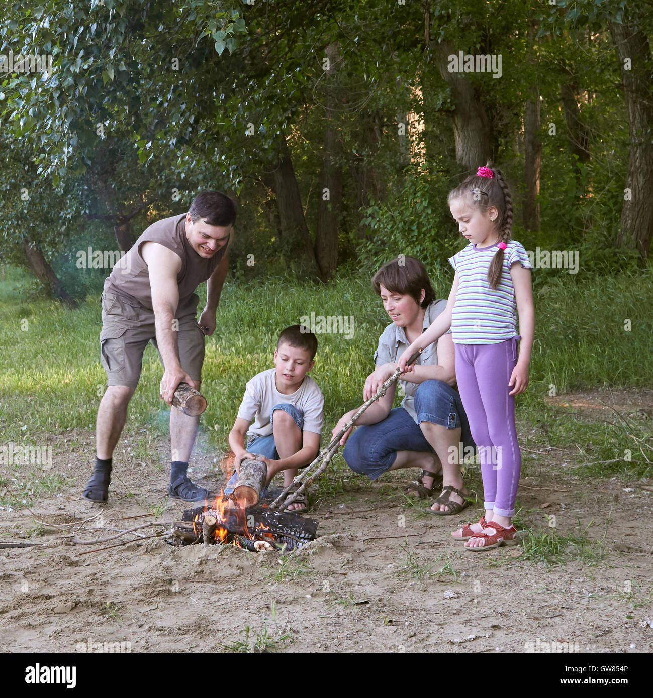 people camping in forest, family active in nature, kindle fire, summer season Stock Photo