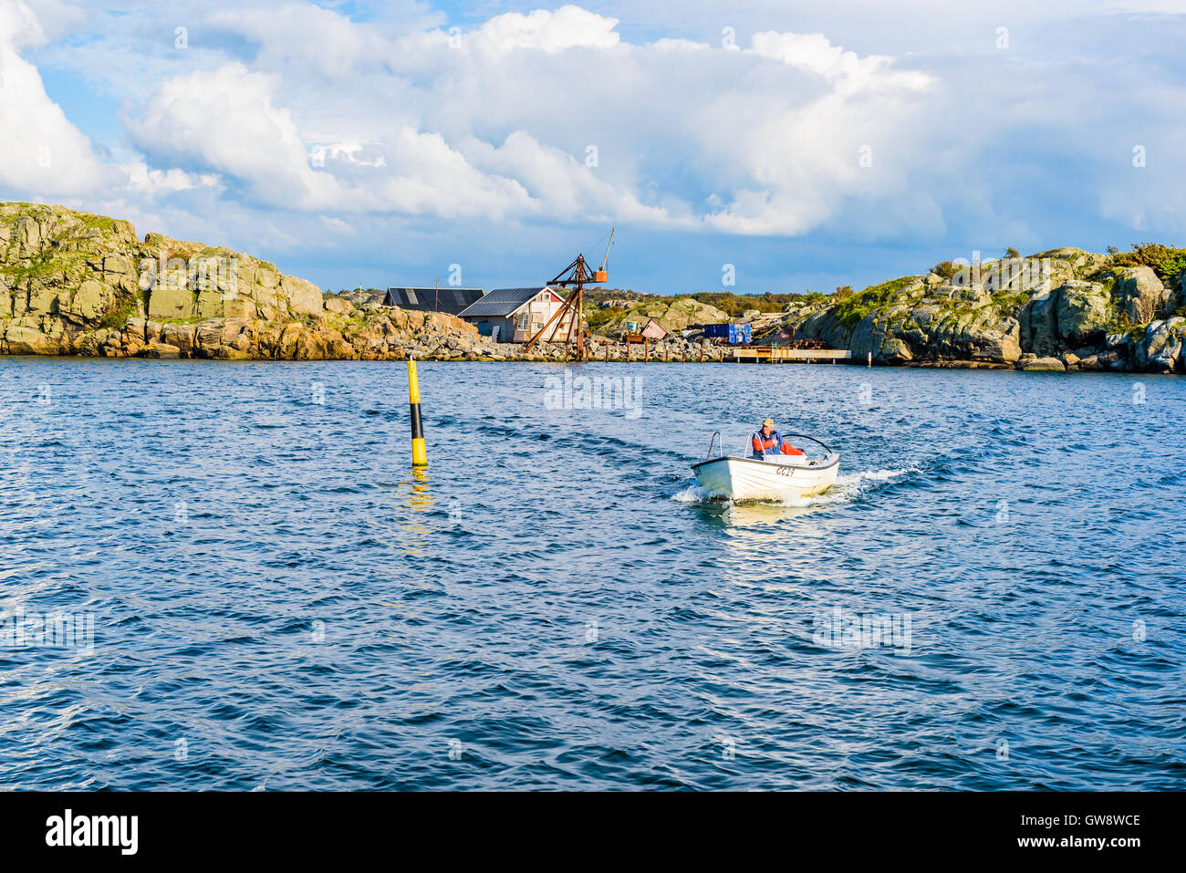 Marstrand, Sweden - September 8, 2016: Male fisherman arriving in small open motorboat going around a navigational marker toward Stock Photo
