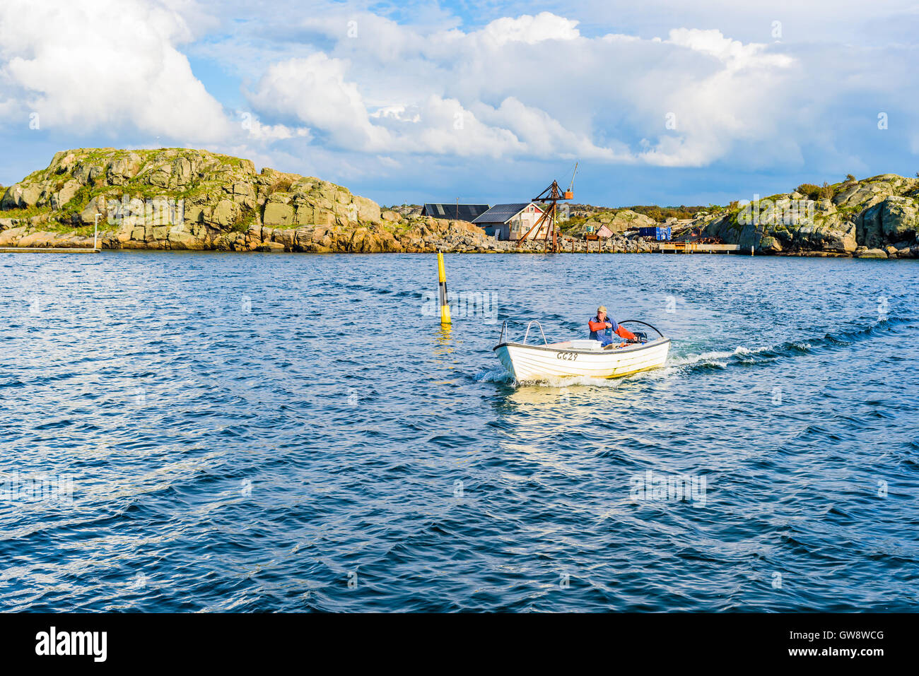 Marstrand, Sweden - September 8, 2016: Male fisherman arriving in small open motorboat going around a navigational marker toward Stock Photo