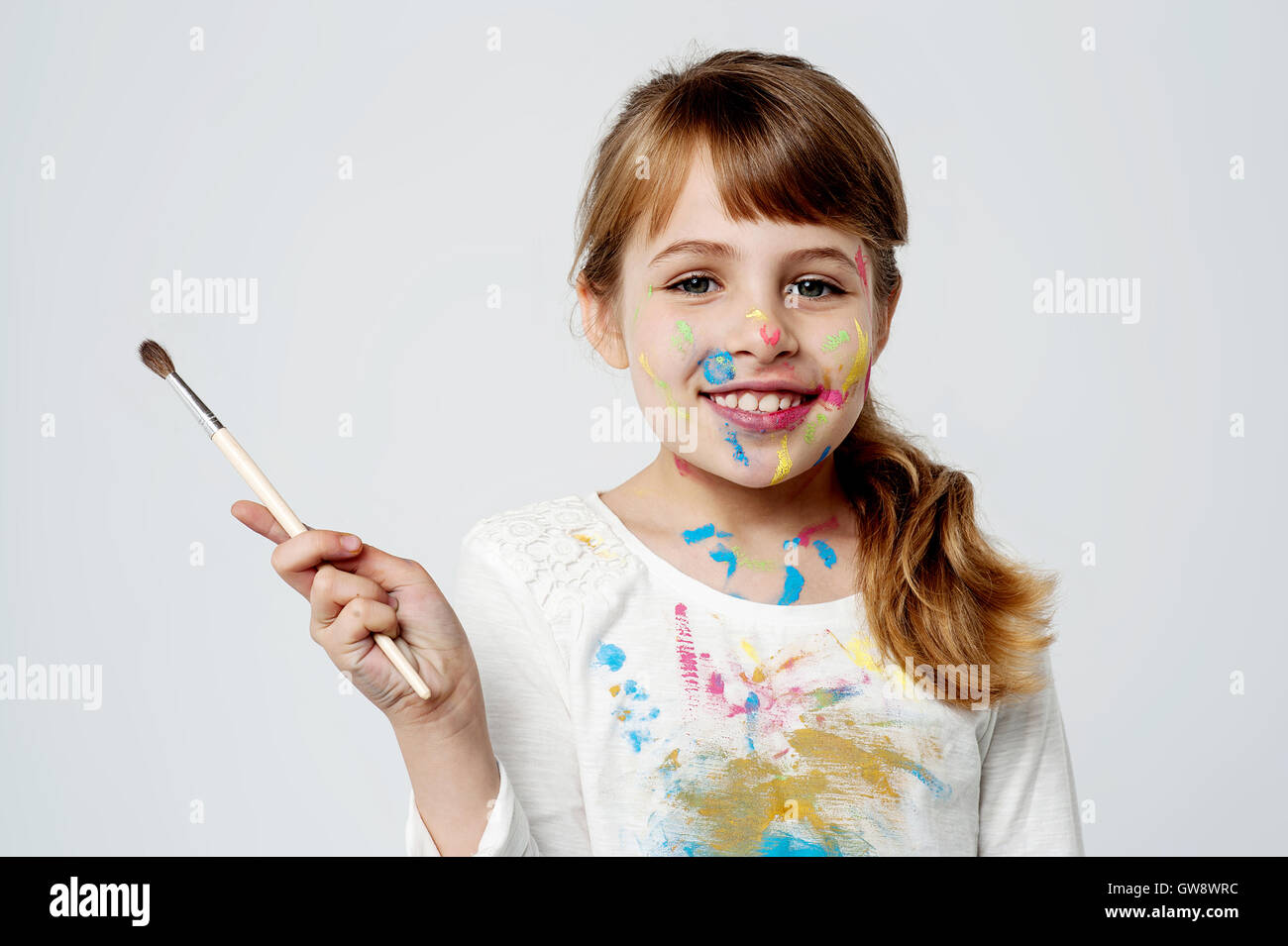 Cute little girl with a painting brush Stock Photo - Alamy