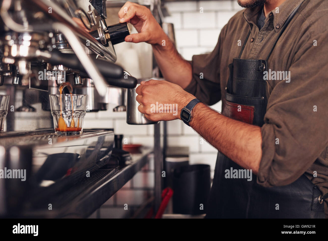 Cropped shot of barista using a coffee maker to prepare a cup of coffee. Cafe worker making a coffee. Stock Photo