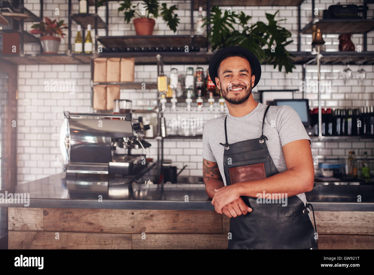 Proud coffee shop owner at the counter. Coffee shop worker in apron and
