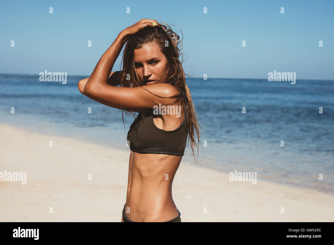 Portrait of beautiful young woman posing in bikini on the beach. Female fashion model posing in swimsuit on the sea shore. Stock Photo
