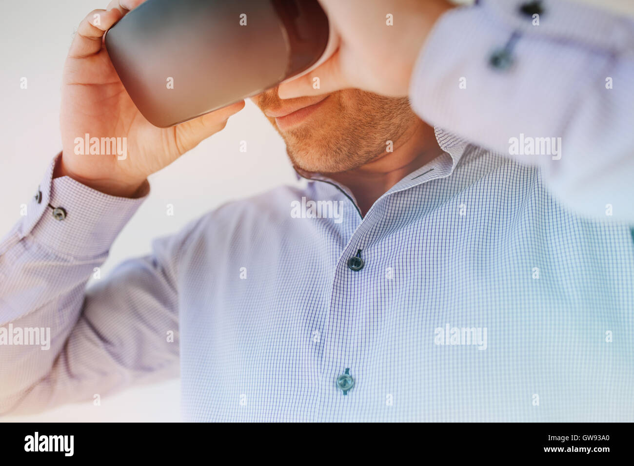 Closeup shot of young businessman using the virtual reality headset. Male executive wearing VR goggles. Stock Photo