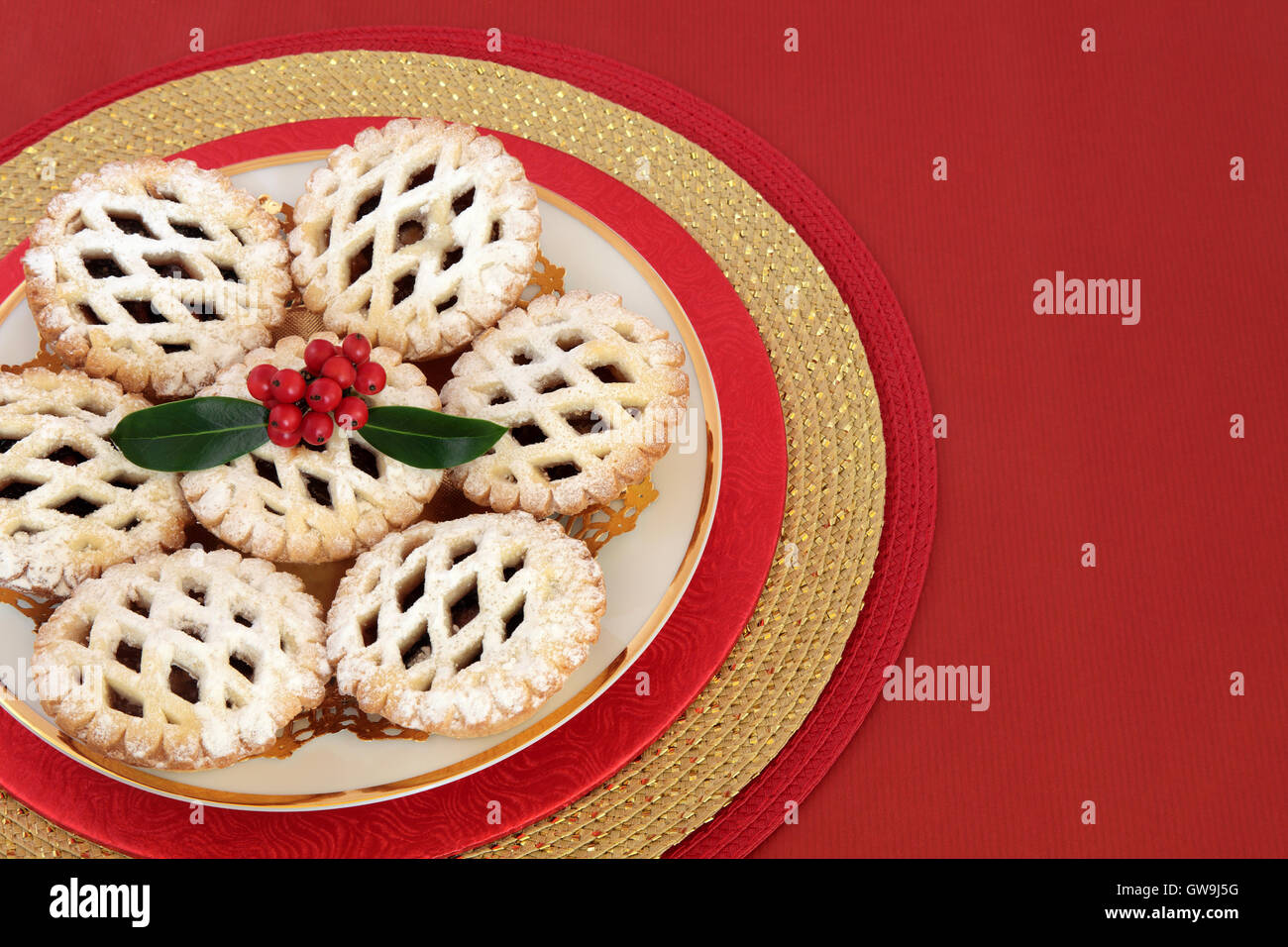 Christmas latticed mince pie cakes with holly on a red background with ...