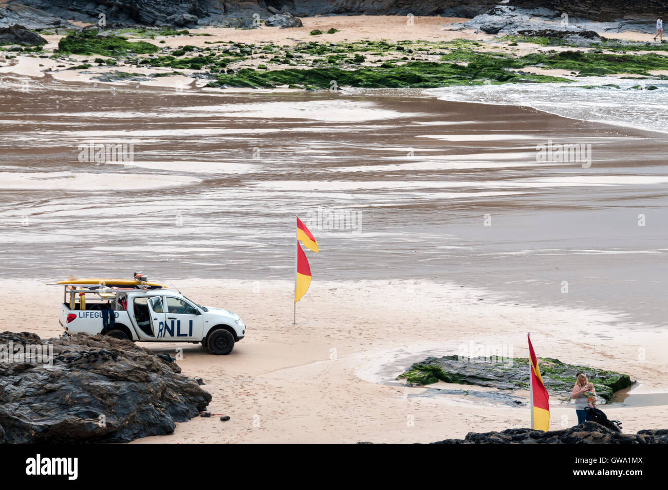 Lifeguards watching swimmers between red & yellow safety flags on the beach at Treyarnon Bay in Cornwall. Stock Photo