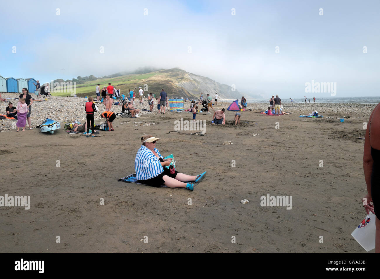 People on the beach at low tide in Charmouth Dorset UK  KATHY DEWITT Stock Photo