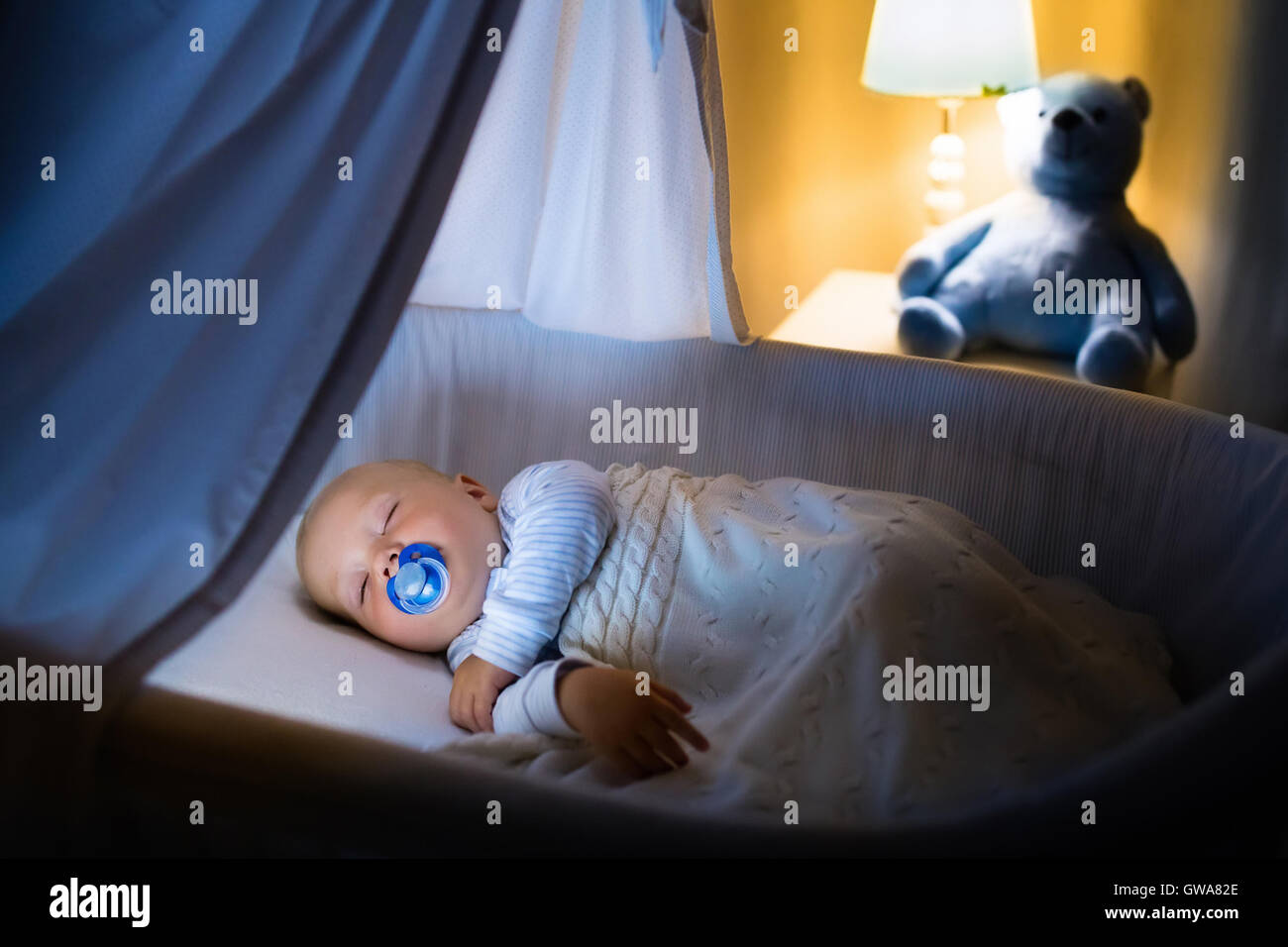 Adorable baby sleeping in blue with canopy at night. Little