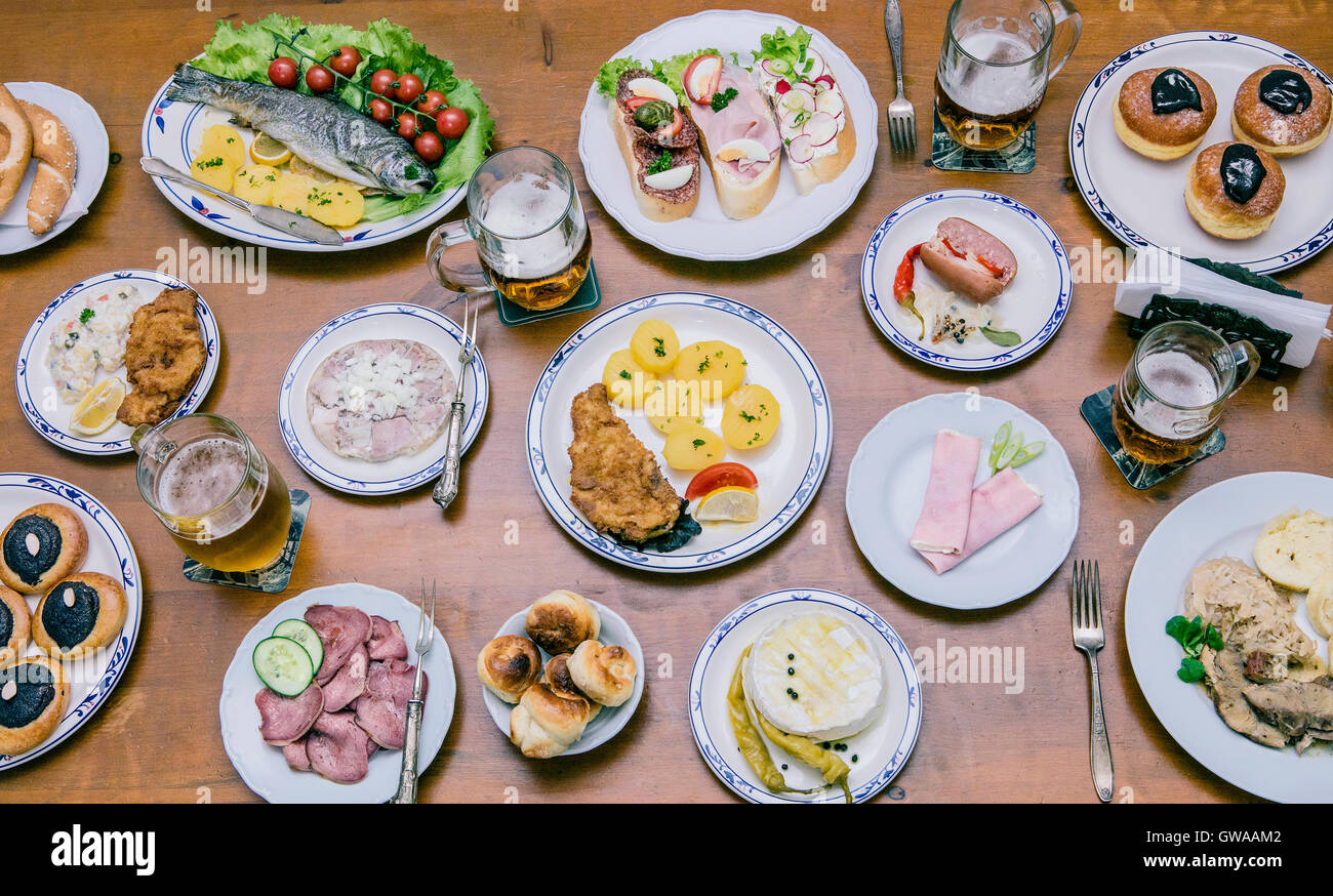 Food from above on a wooden table with young people around eating a variety of food Stock Photo