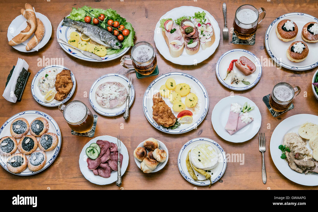 Food from above on a wooden table with young people around eating a variety of food Stock Photo