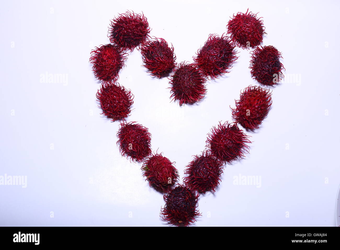 Heart with rambutan against a white background Stock Photo - Alamy