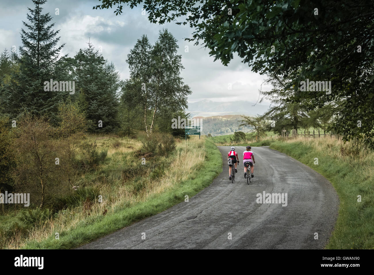 Two women cyclist cresting a hill in the English Lake District, Cumbria