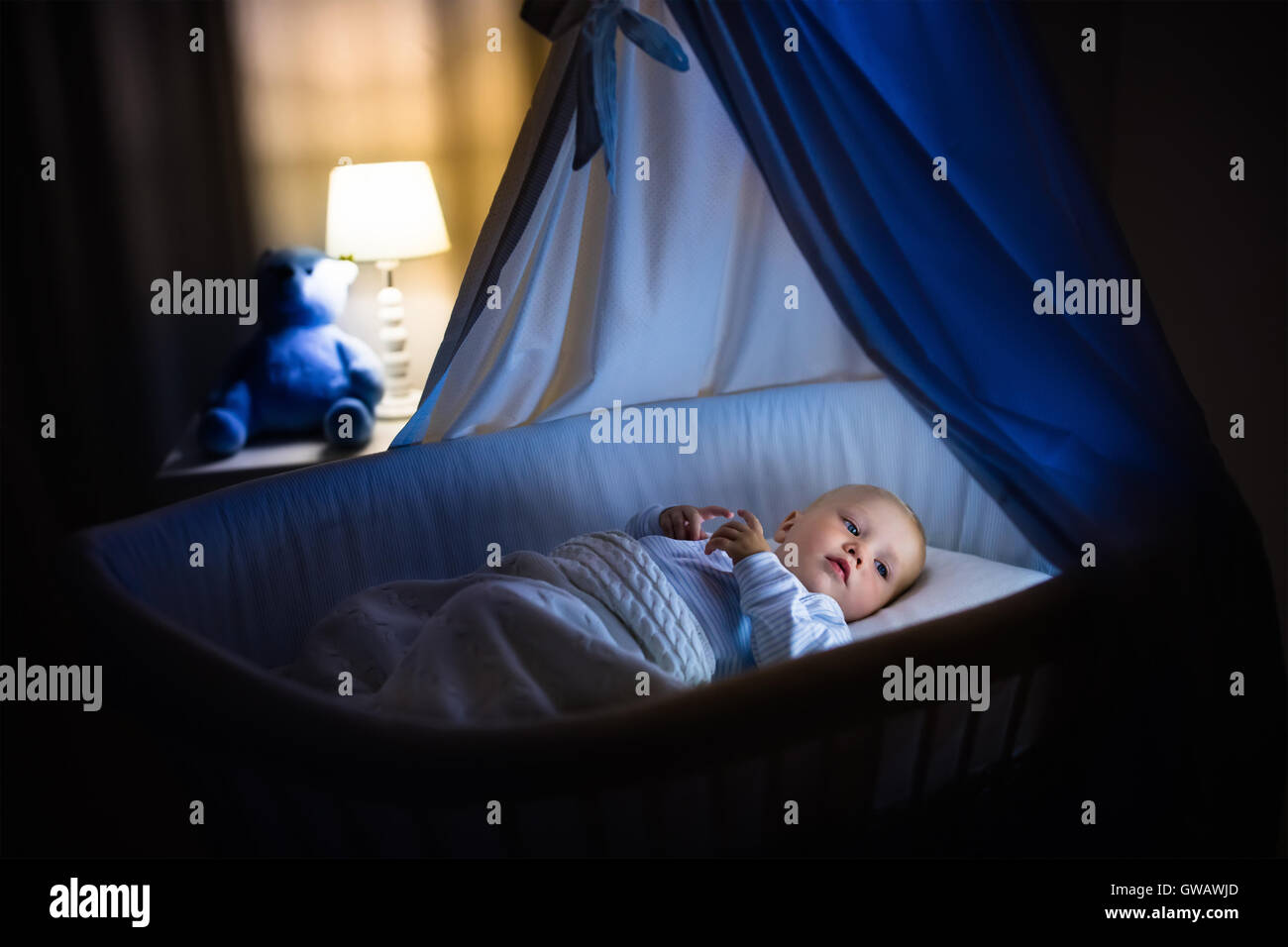 Adorable baby sleeping in blue with canopy at night. Little