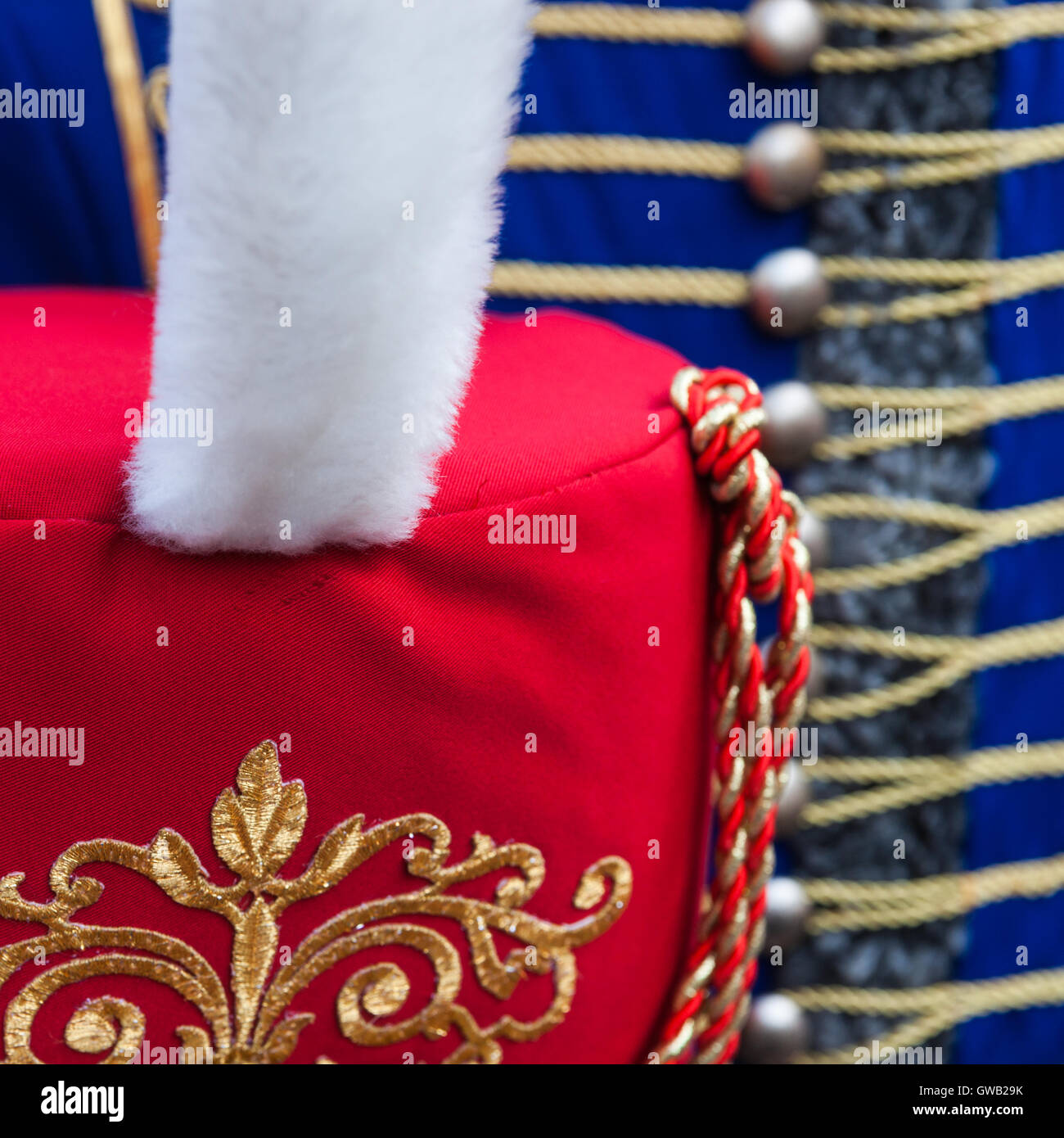 Details of red hussar busby hat with white fur plume against the background of blue dolman jacket. Stock Photo