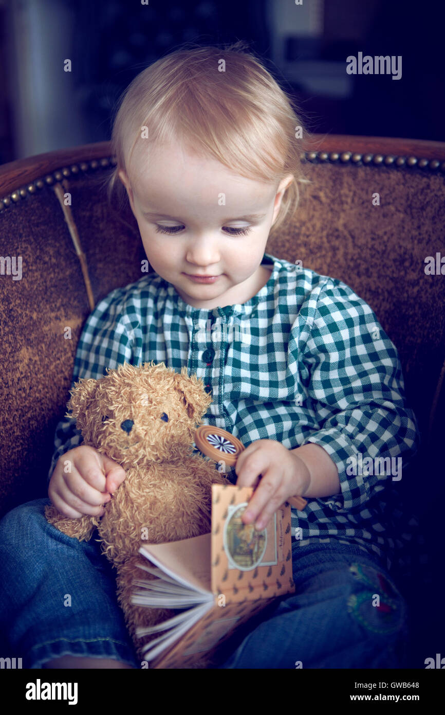 Young child reading a book to teddy bear Stock Photo