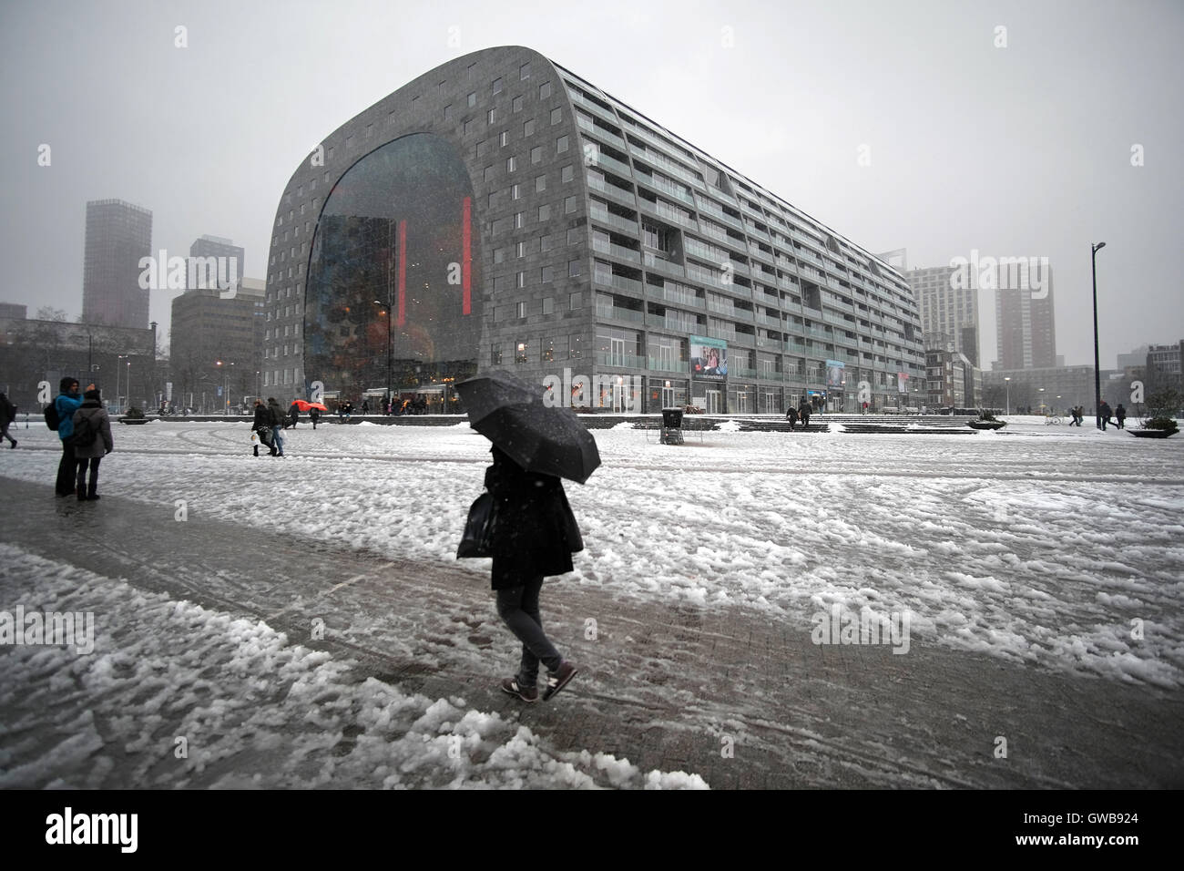 Rotterdam's Marktal on a cold snowy winter's day a shopper rushes with their black umbrella Stock Photo