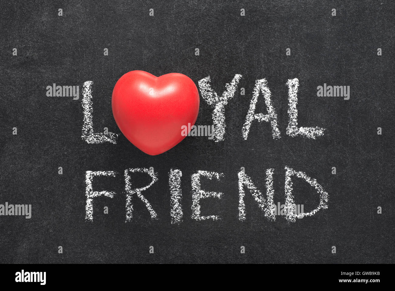 loyal friend phrase handwritten on blackboard with heart symbol instead of O Stock Photo