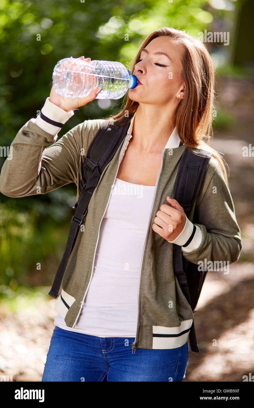Woman drinking water whilst walking outdoors Stock Photo