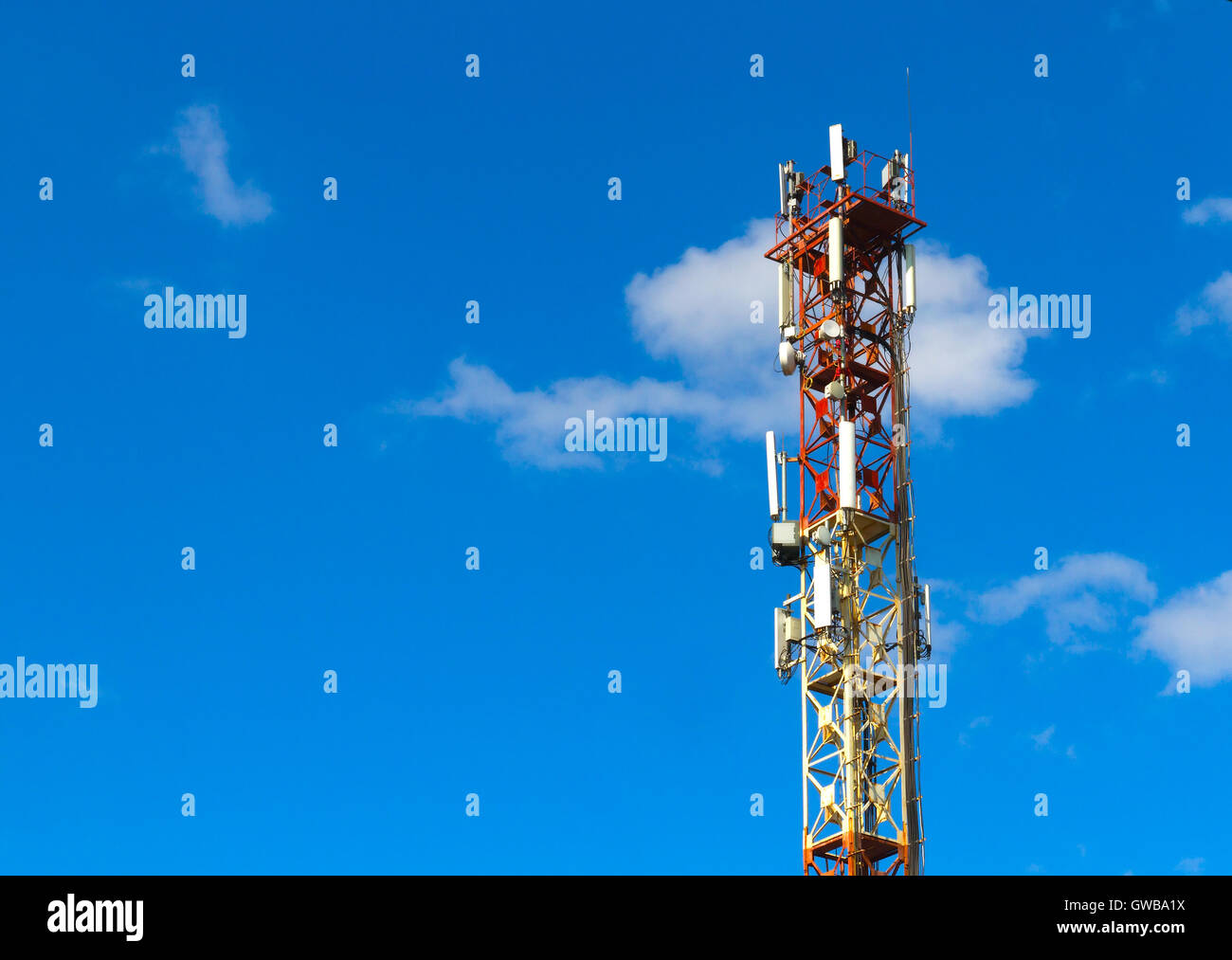 Cellular connection tower with transmitters and antenns over a blue sky background. Stock Photo