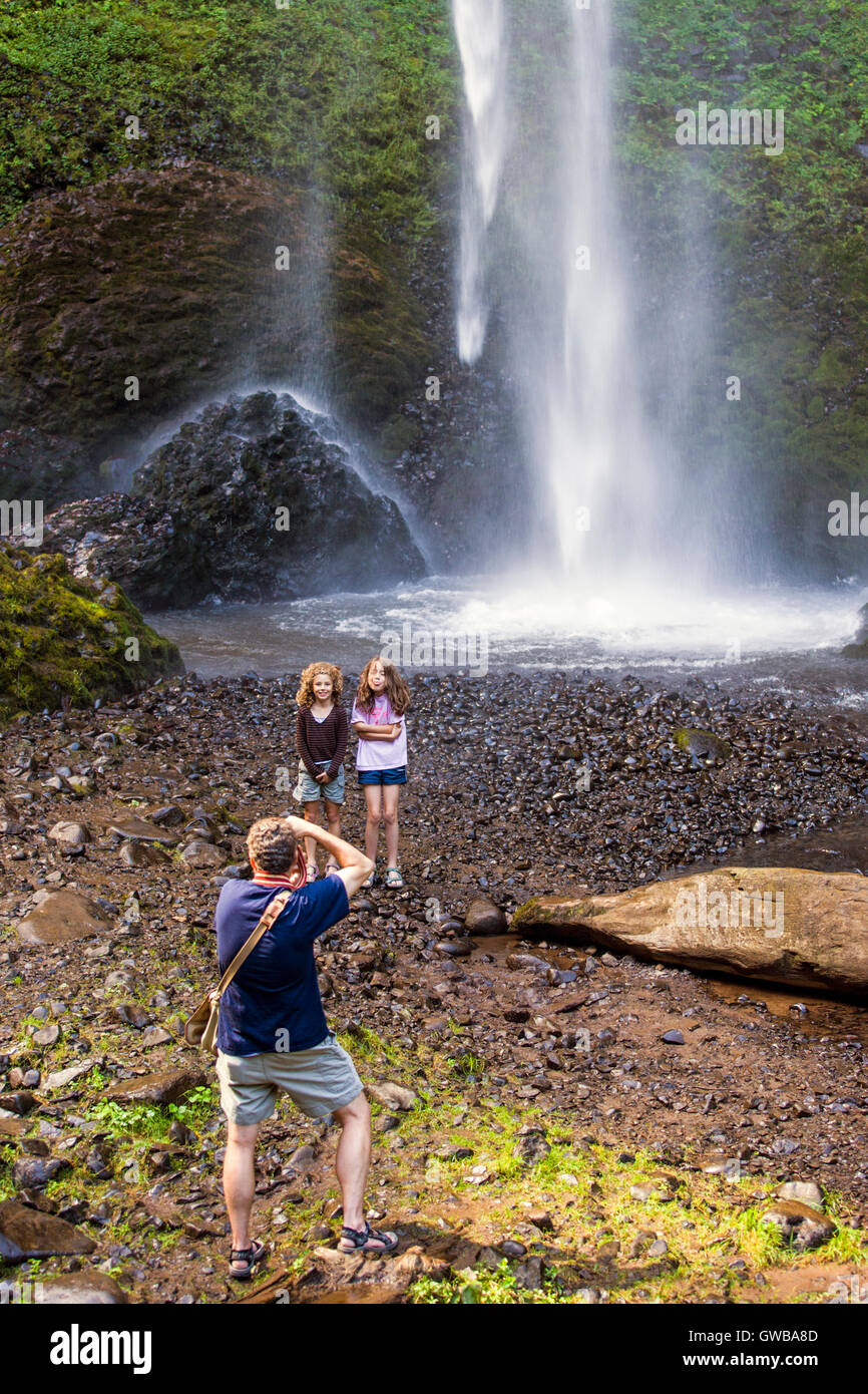 Father photographing young daughters; Latourell Falls, located in the Columbia River Gorge in Oregon, USA Stock Photo