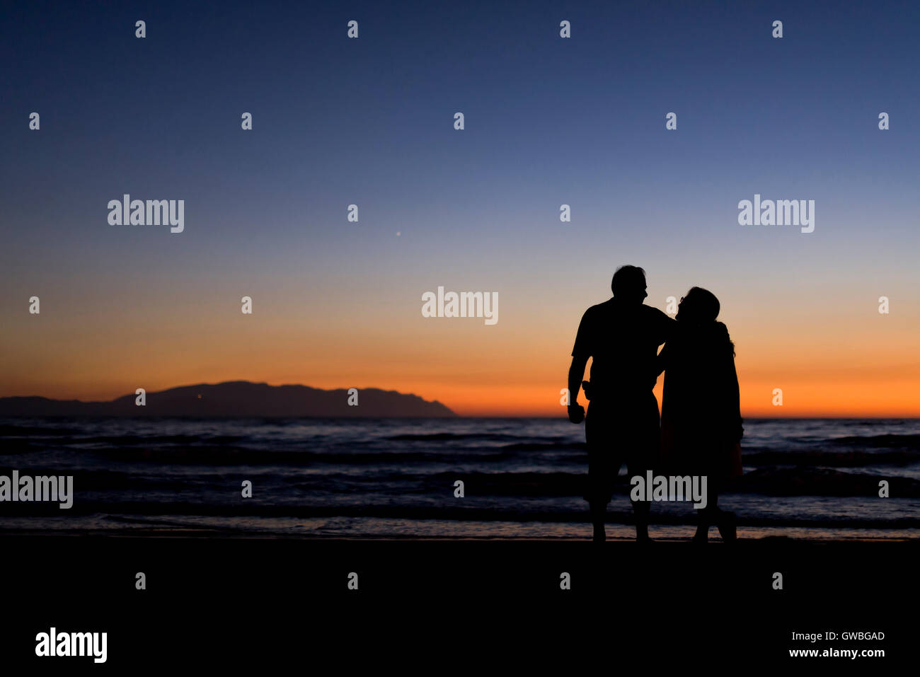 Silhouette of a couple on the beach at dusk time Stock Photo - Alamy