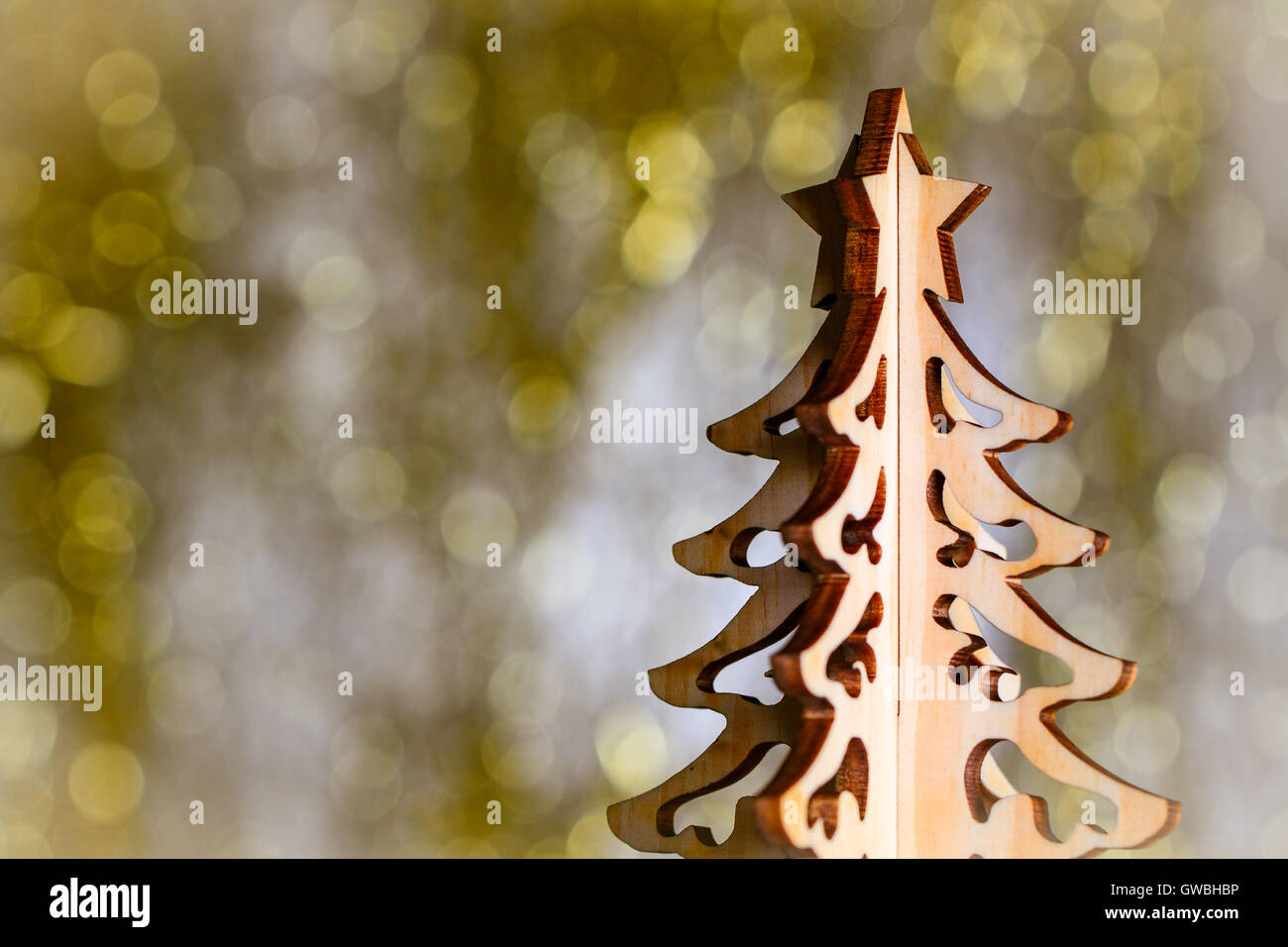 Wooden christmas tree on gold bokeh background. Decorative xmas card with copy space. Stock Photo