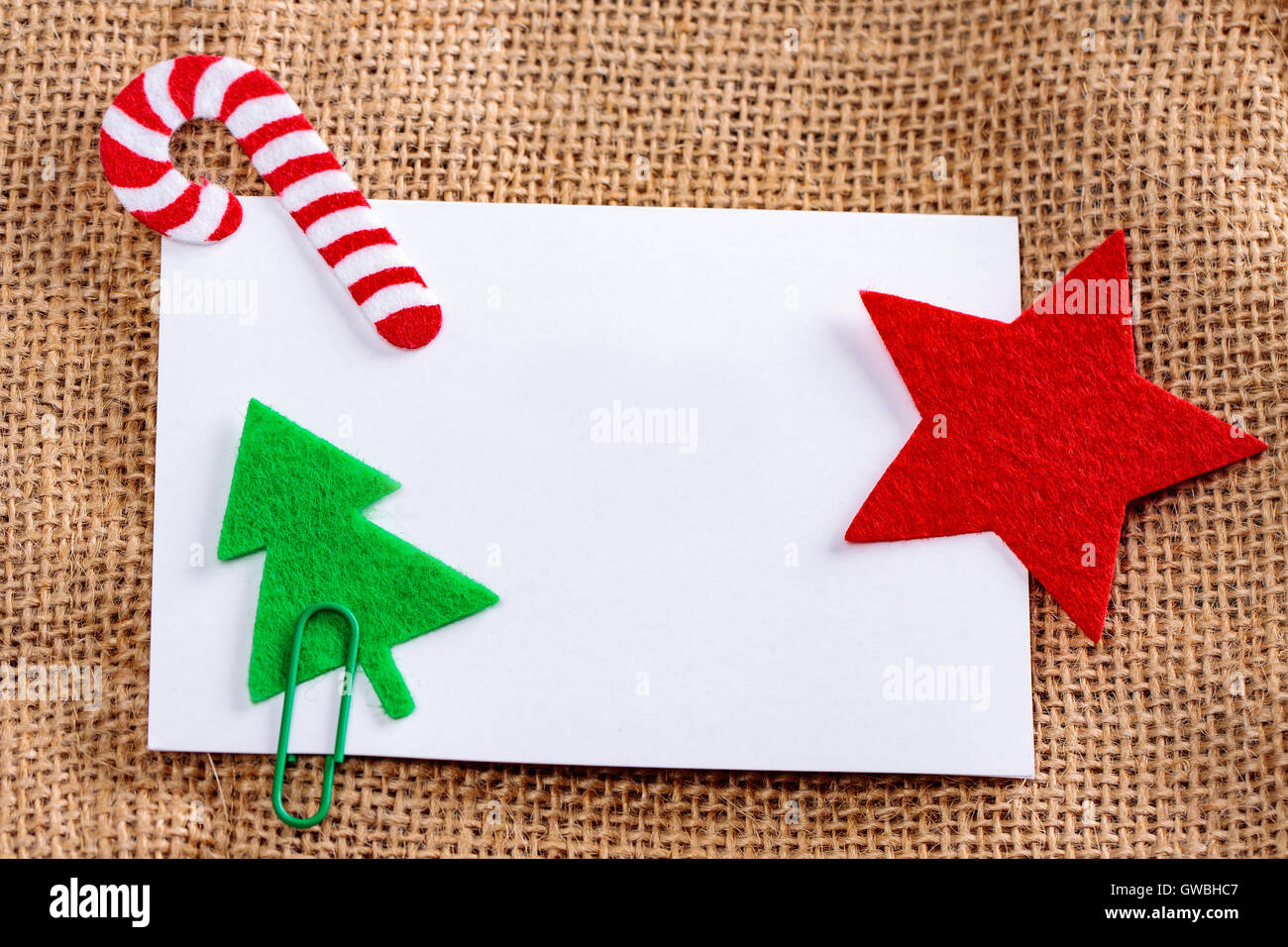 Blank card with christmas felt decorations on jute background. Stock Photo