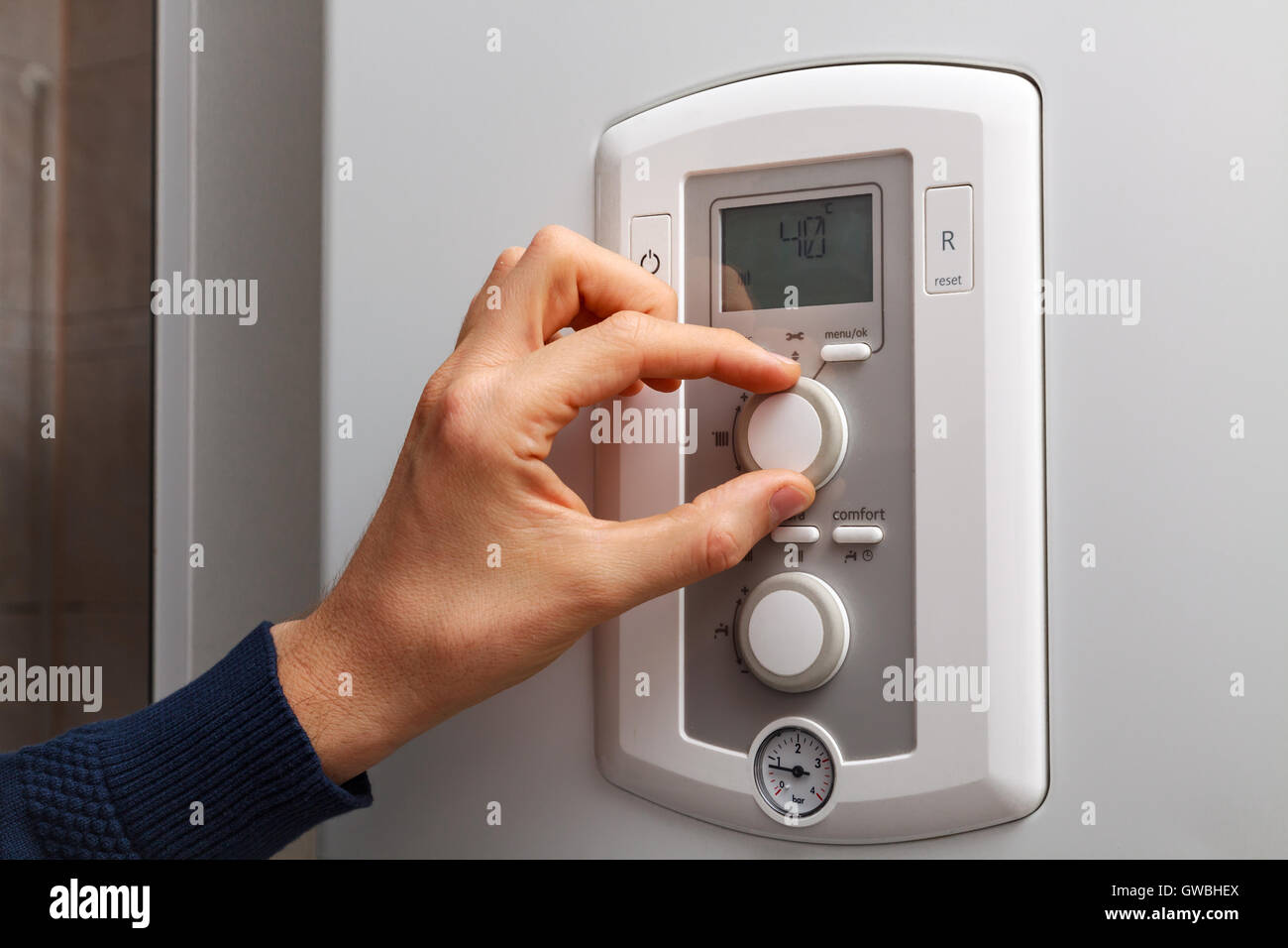 Men hand regulate low temperature on 40 degree in control panel of central heating. Stock Photo