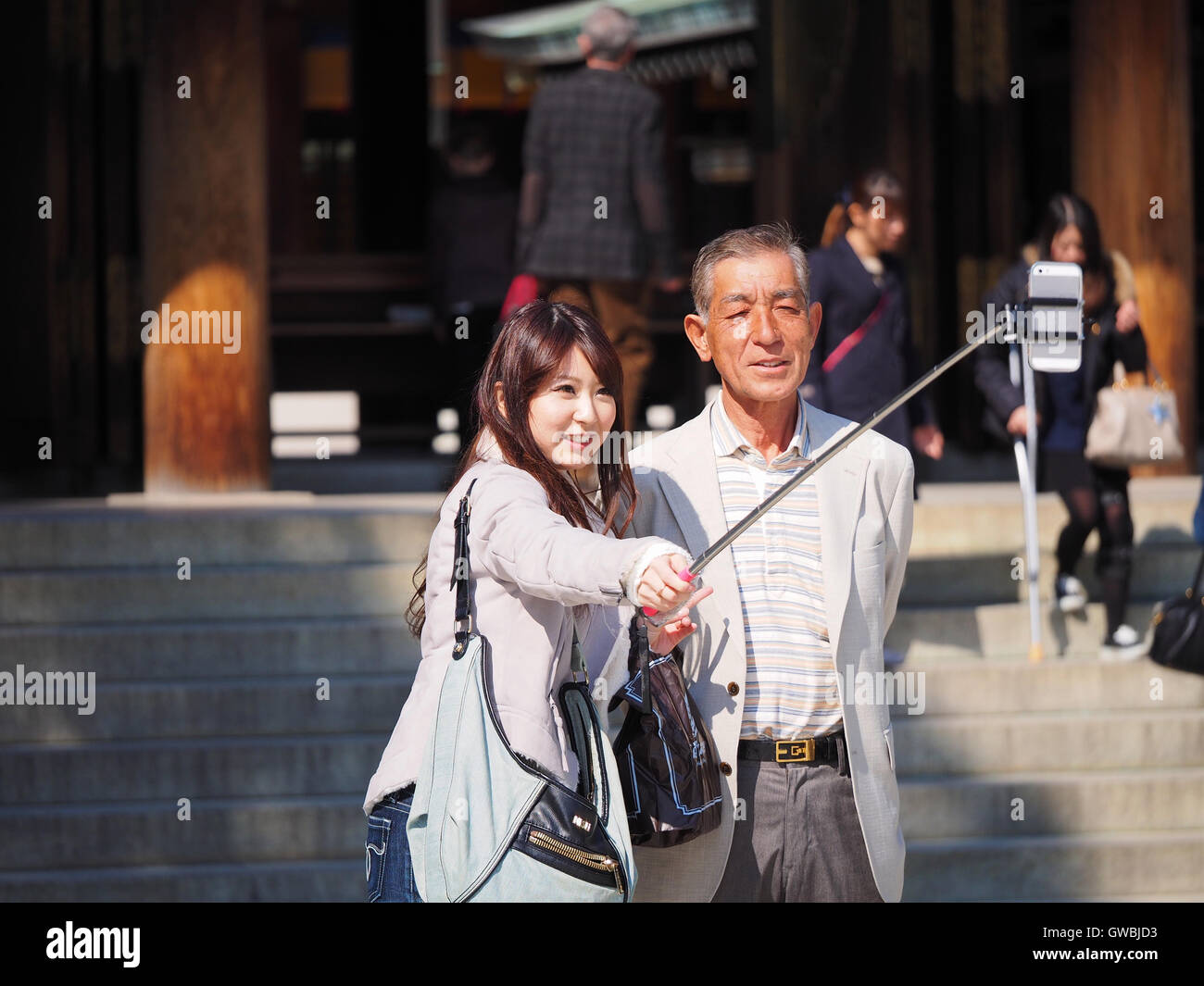 A young female with a middle aged male taking a wefie with a selfie stick at Meiji Shrine, Tokyo, Japan Stock Photo