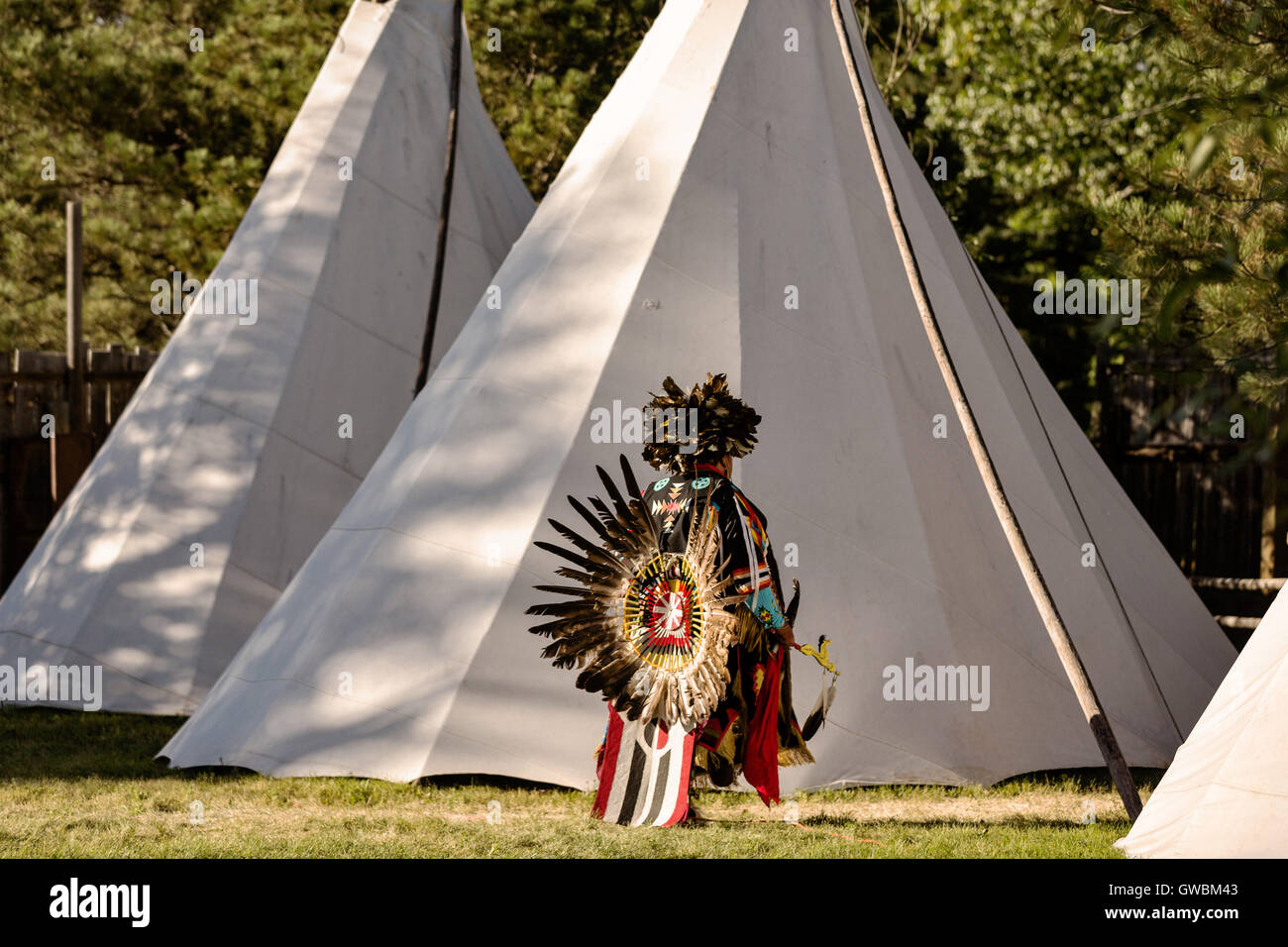 A Native American dancer from the Arapahoe people dressed in traditional costume returns to a teepee camp at the Indian Village during Cheyenne Frontier Days July 25, 2015 in Cheyenne, Wyoming. Frontier Days celebrates the cowboy traditions of the west with a rodeo, parade and fair. Stock Photo