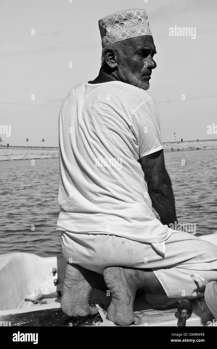 Sur, Oman, October 23, 2013: Omani fisherman at work. He is wearing the traditional omani hat, the kumma, used during unofficial Stock Photo