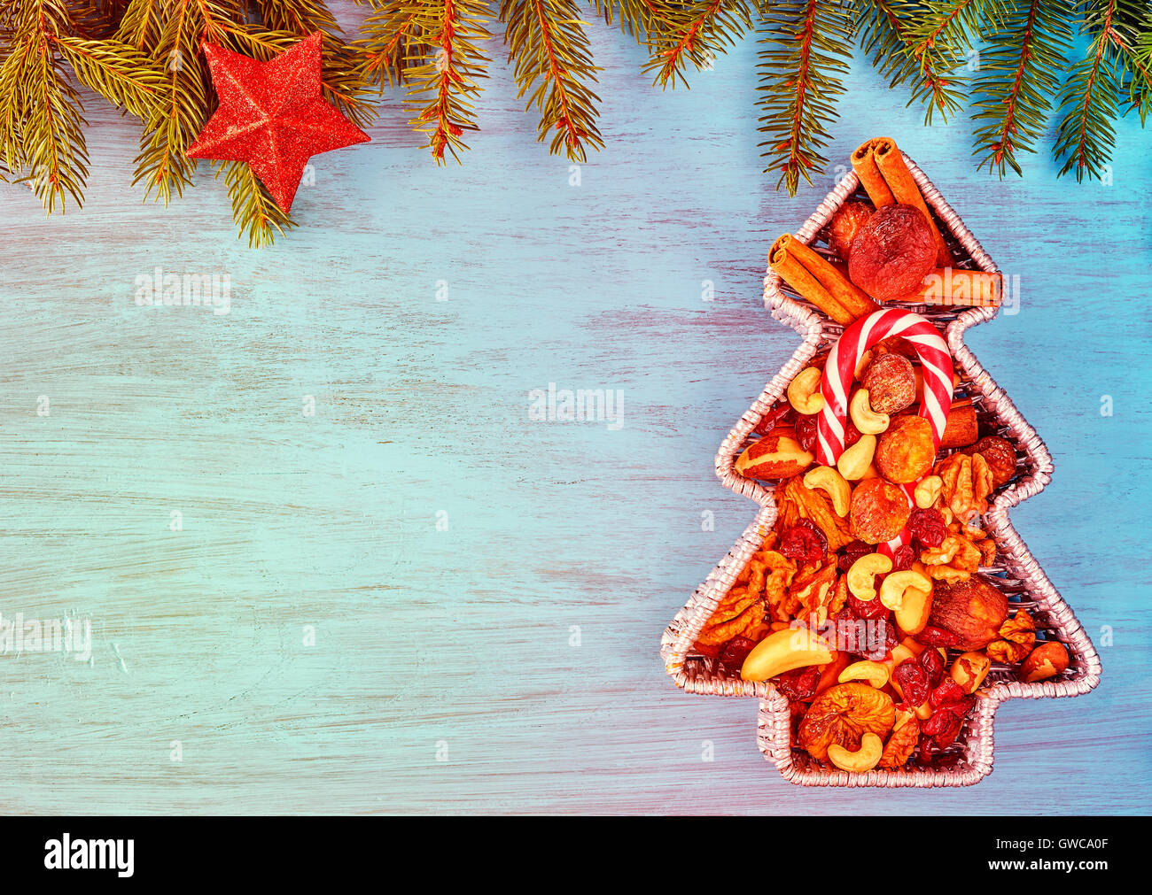 Vintage toned Christmas tree shaped container filled with nuts and dried fruits on a rustic wooden table, top view with copy spa Stock Photo