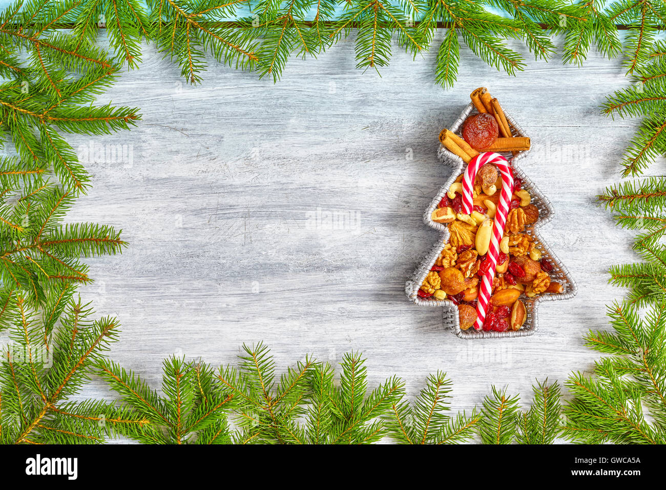 Christmas tree shaped container filled with nuts and dried fruits on a rustic wooden table, top view with copy space. Stock Photo