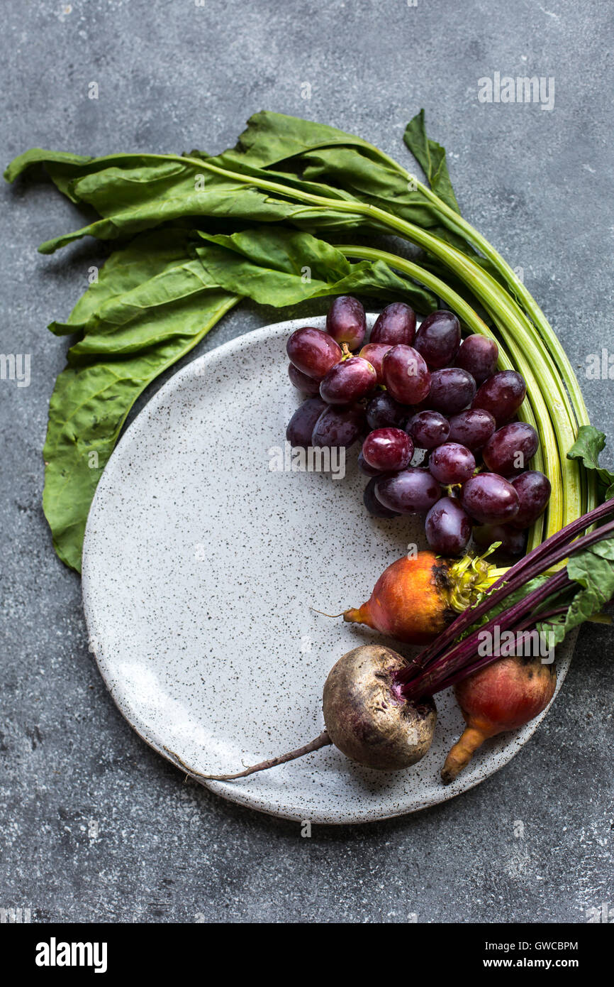 Freshly picked beets and red grapes are photographed from the top view. Stock Photo