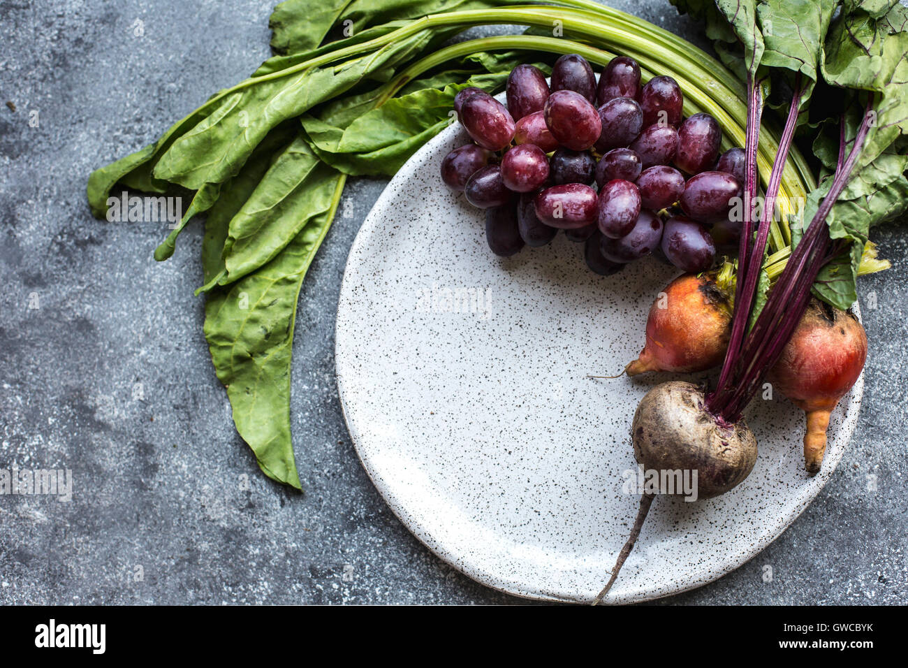 Freshly picked beets and red grapes are photographed from the top view. Stock Photo