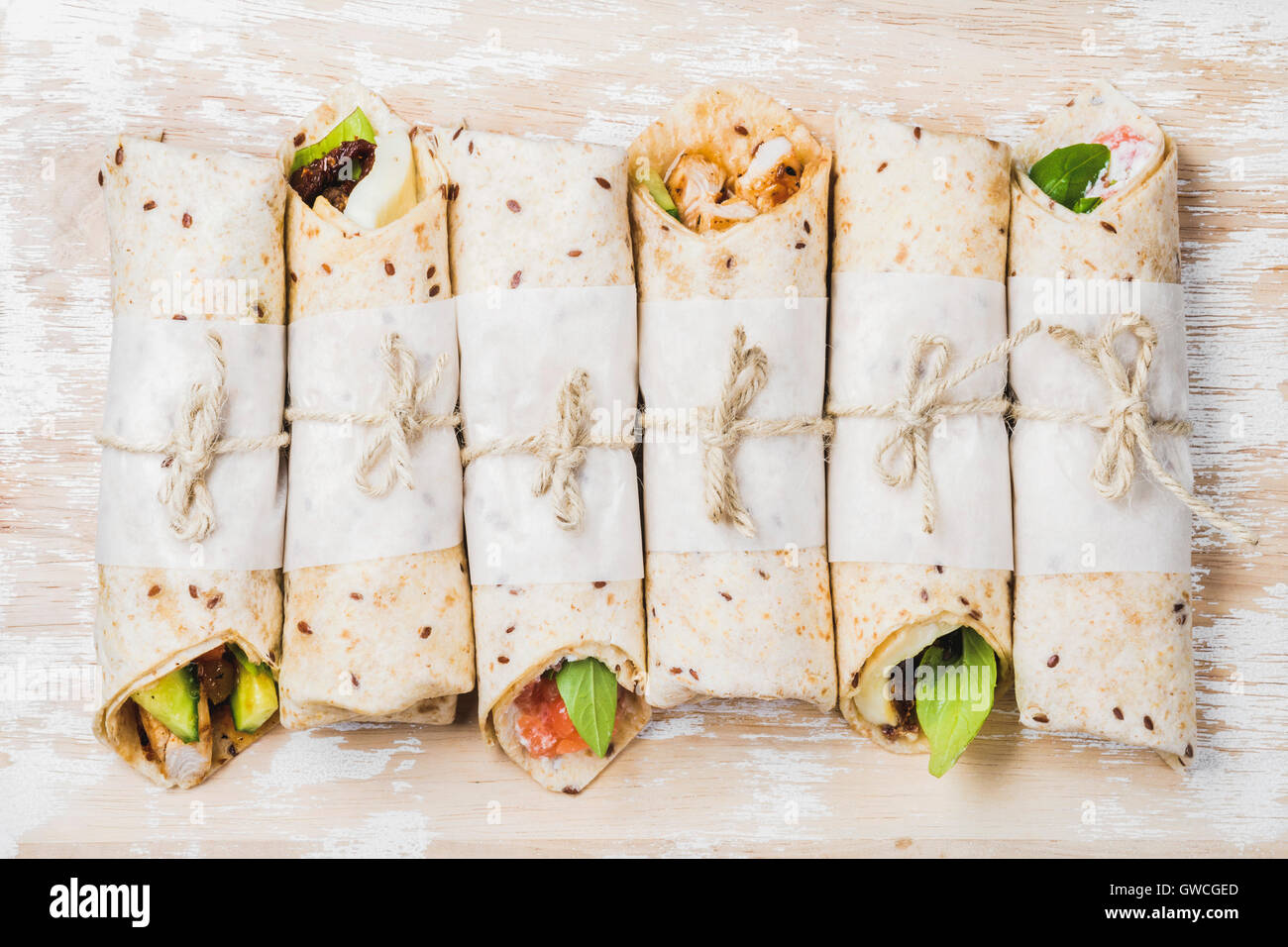 Tortilla wraps with various fillings on shabby white painted wooden