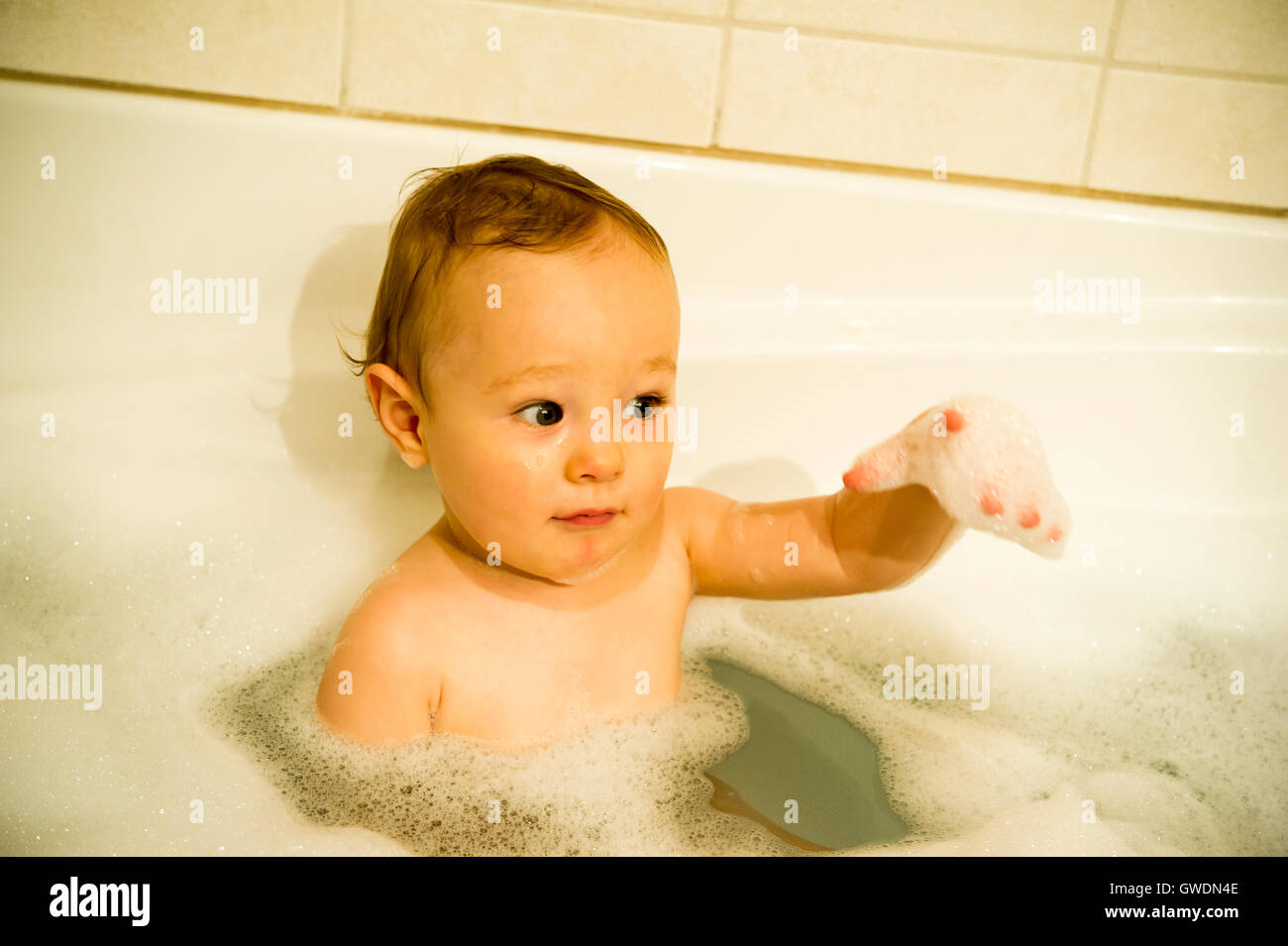 One year old boy playing with foam in a bath tub Stock Photo