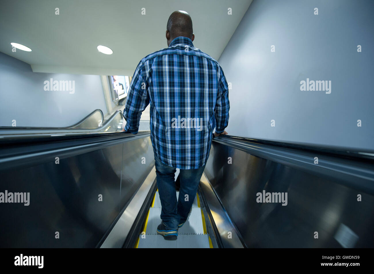 Man on an escalator going down Stock Photo