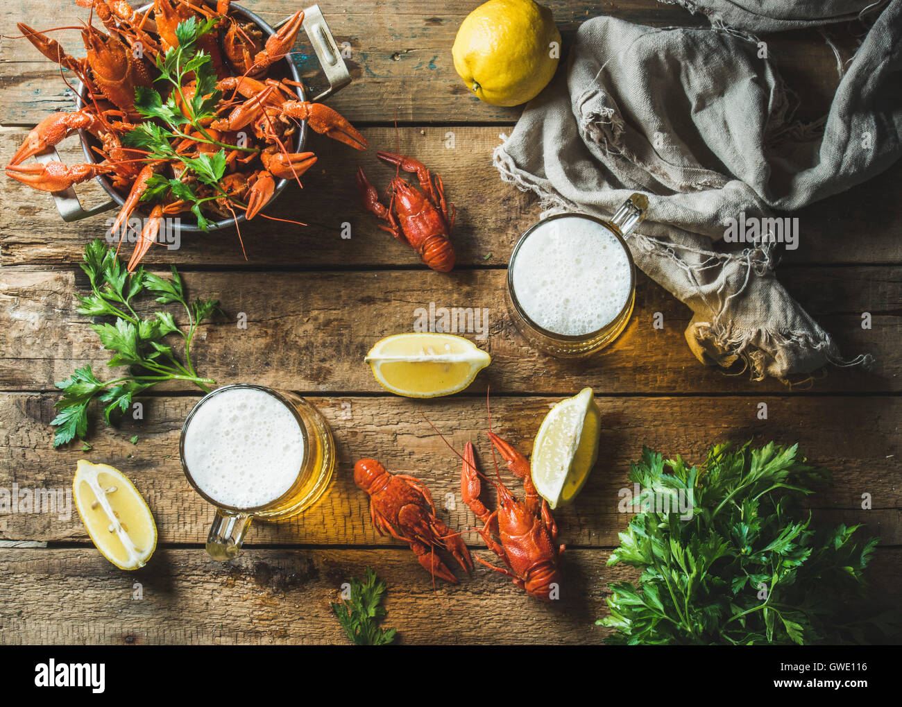 Two pints of wheat beer and boiled crayfish with lemon and parsley over old wooden rustic background, top view, horizontal compo Stock Photo