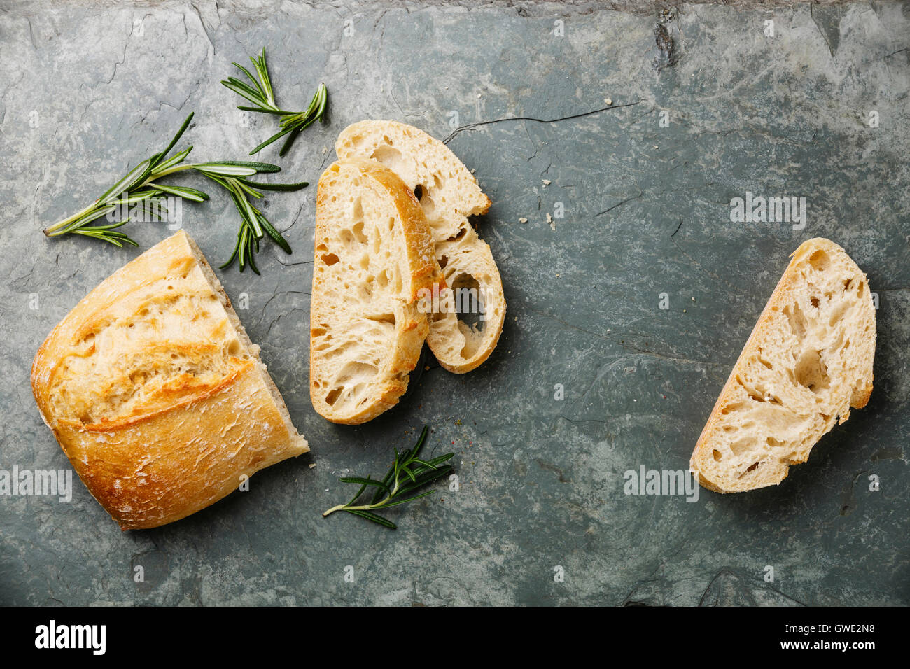Sliced bread Ciabatta and rosemary on gray stone slate background Stock Photo