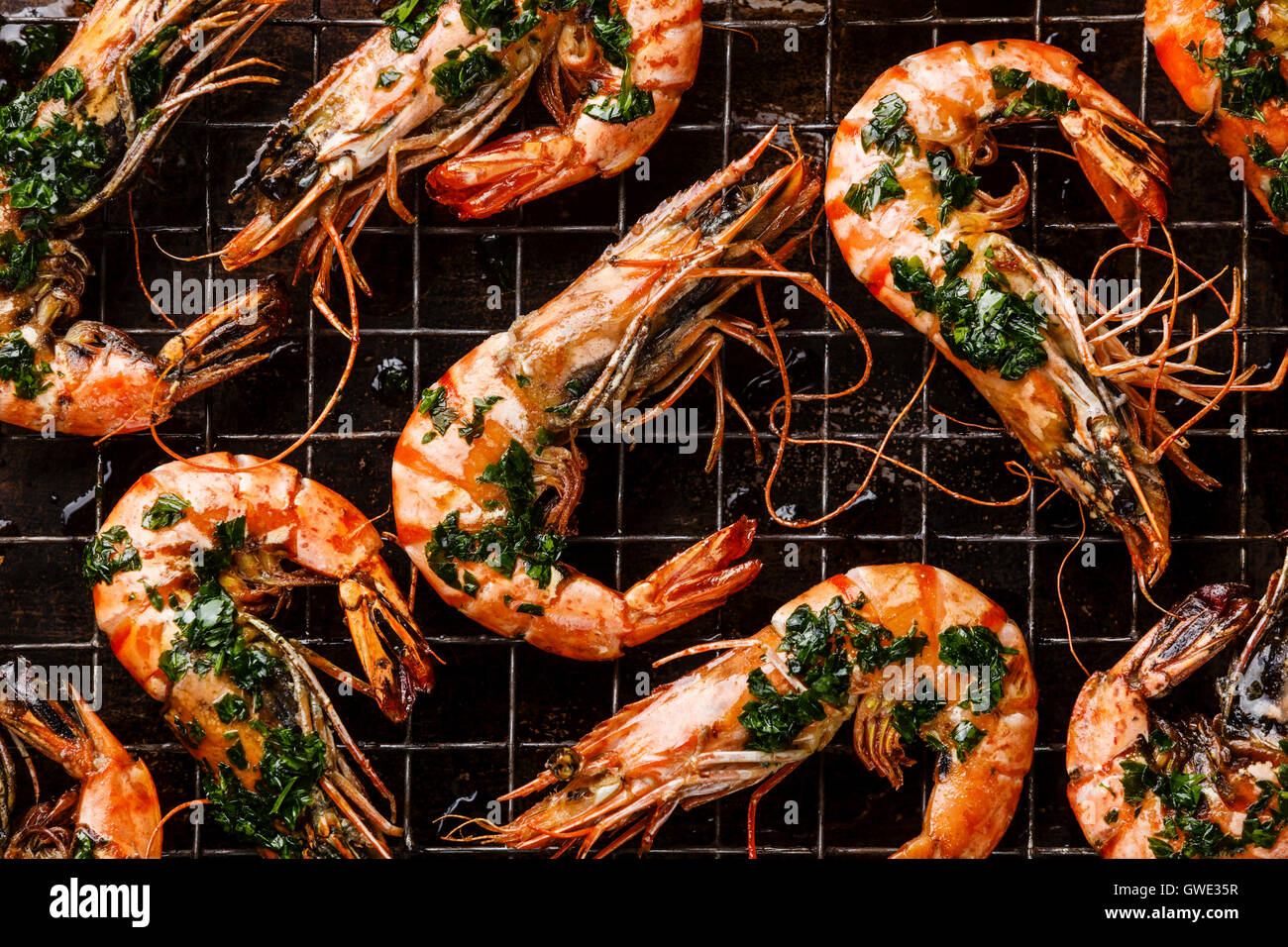 Roasted tiger prawns with green sauce on metal baking sheet background close up Stock Photo